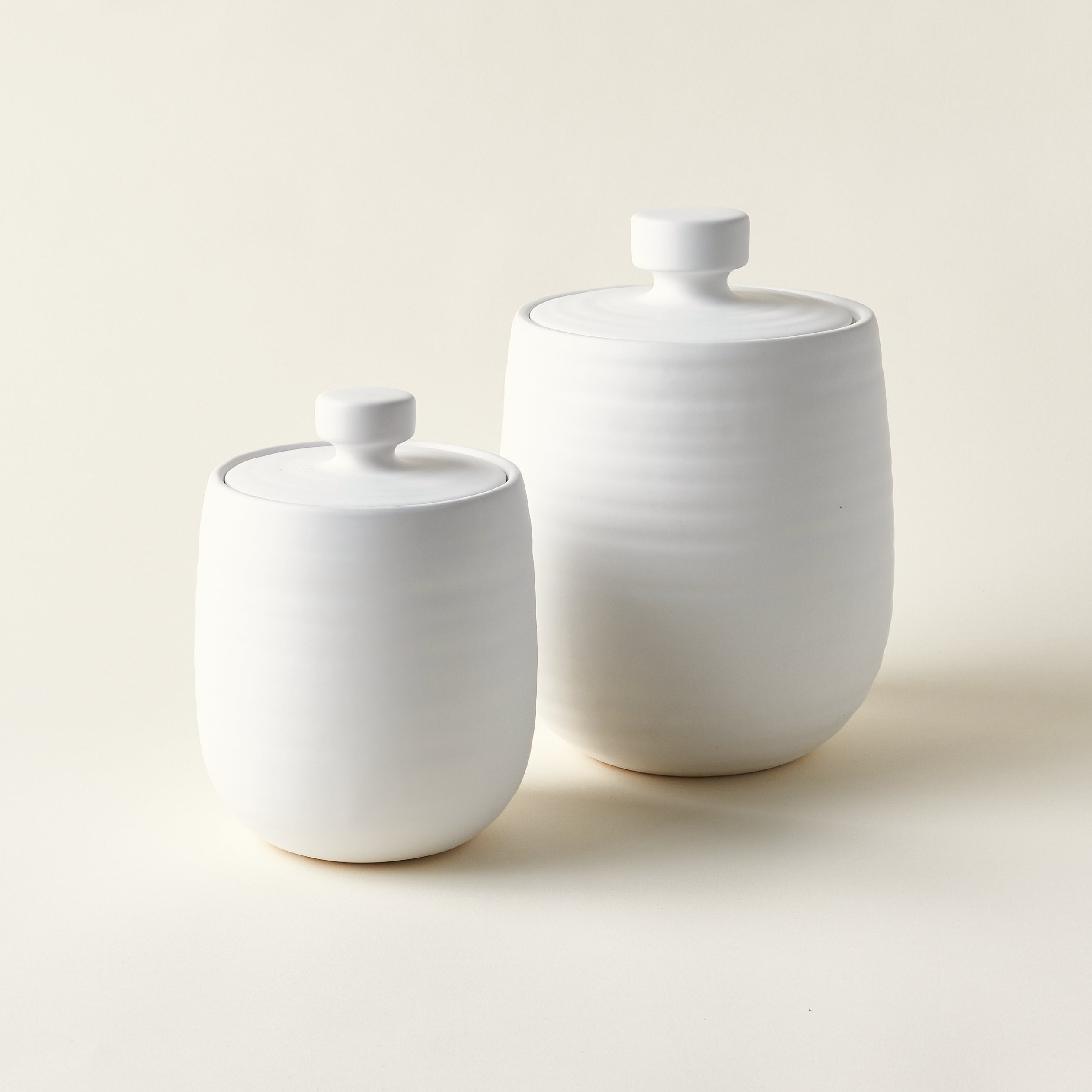 Set of two sleek, white storage canisters.