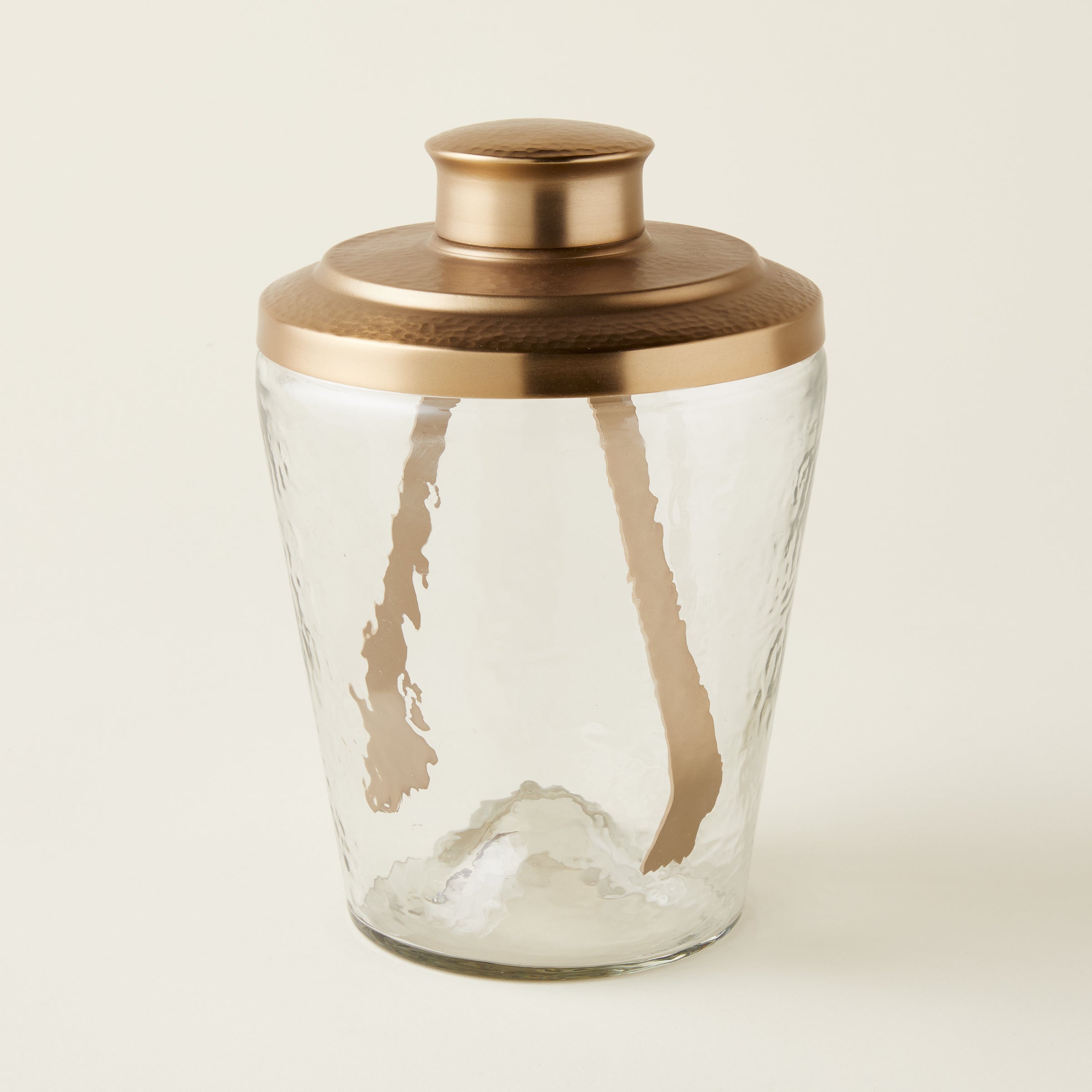 Ana glass ice bucket with a pebbled texture and a hammered brass lid, accompanied by brass tongs.