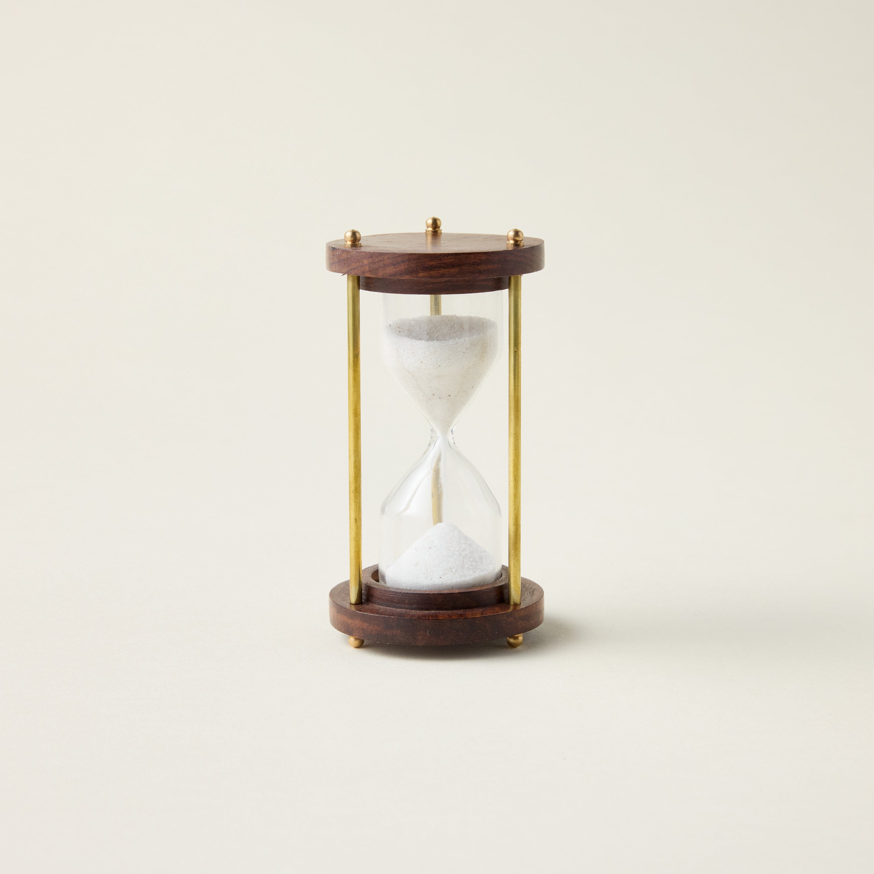 Antique hourglass with a solid wood and brass frame, styled as a timeless and sophisticated decor accent.
