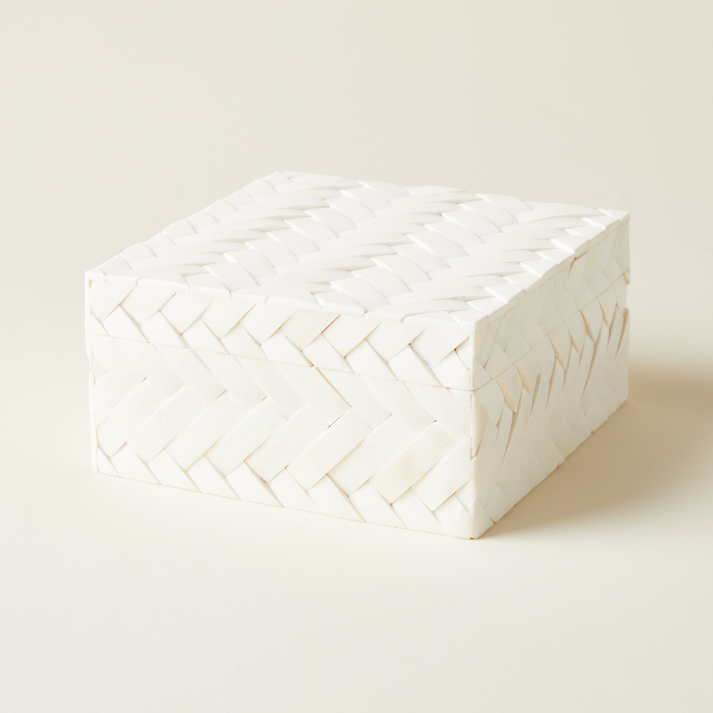 A small decorative storage box with a black and white geometric pattern made from inlaid bone.