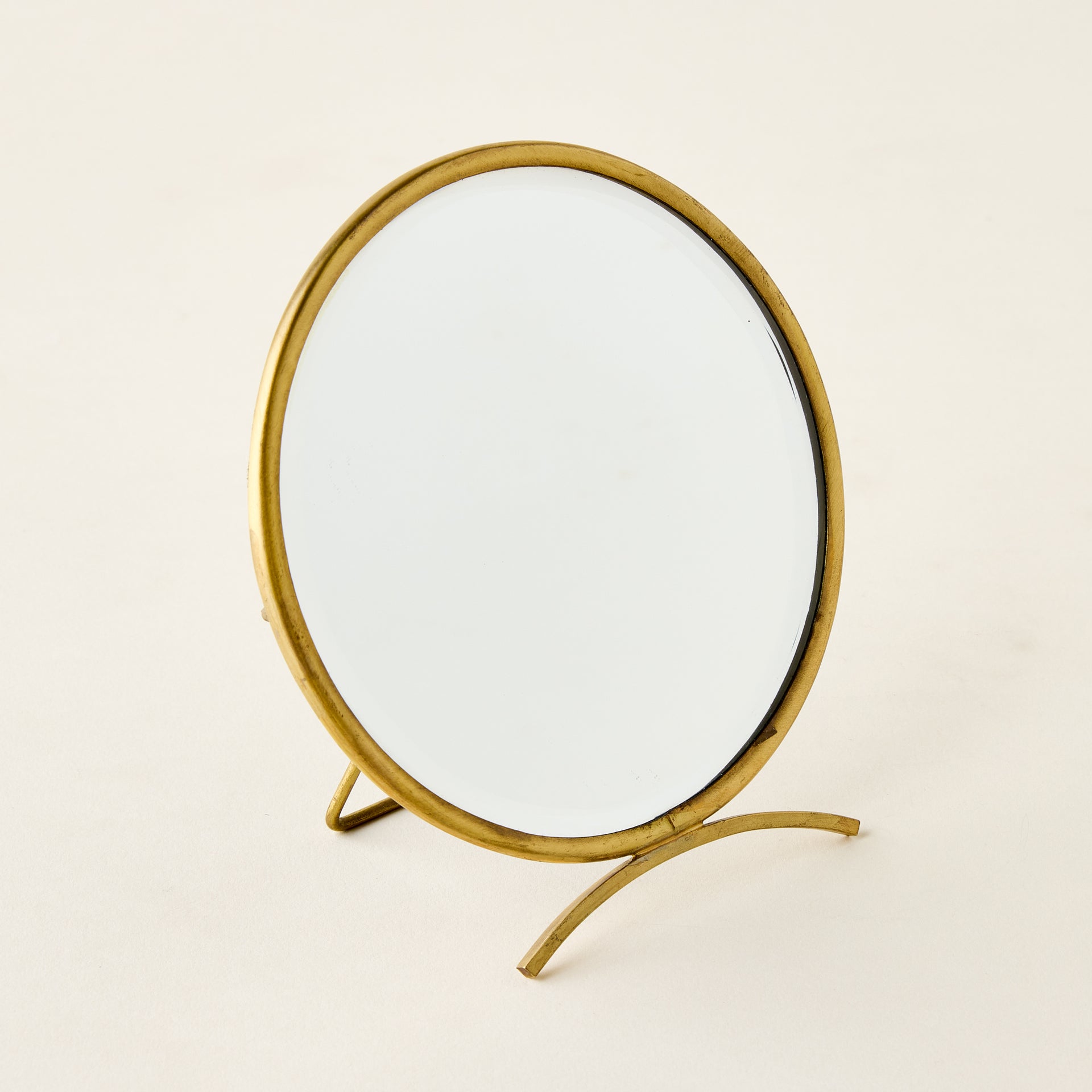 Vintage-inspired brass folding mirror with a round shape and a warm antique finish.