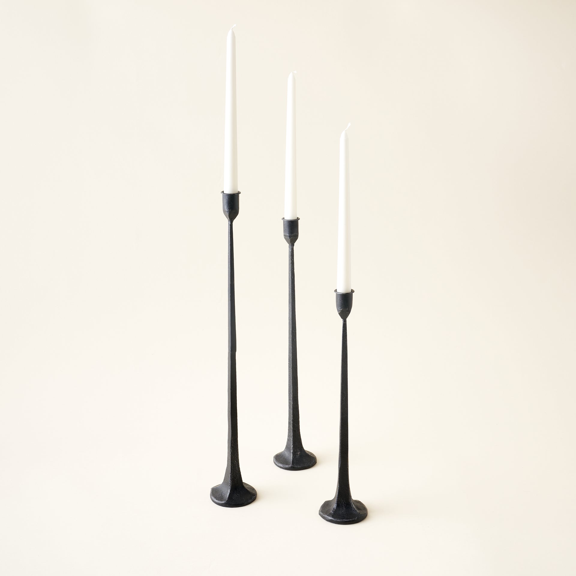 Set of three cast iron taper candle holders with a minimalist, sculptural design in a timeless black finish.
