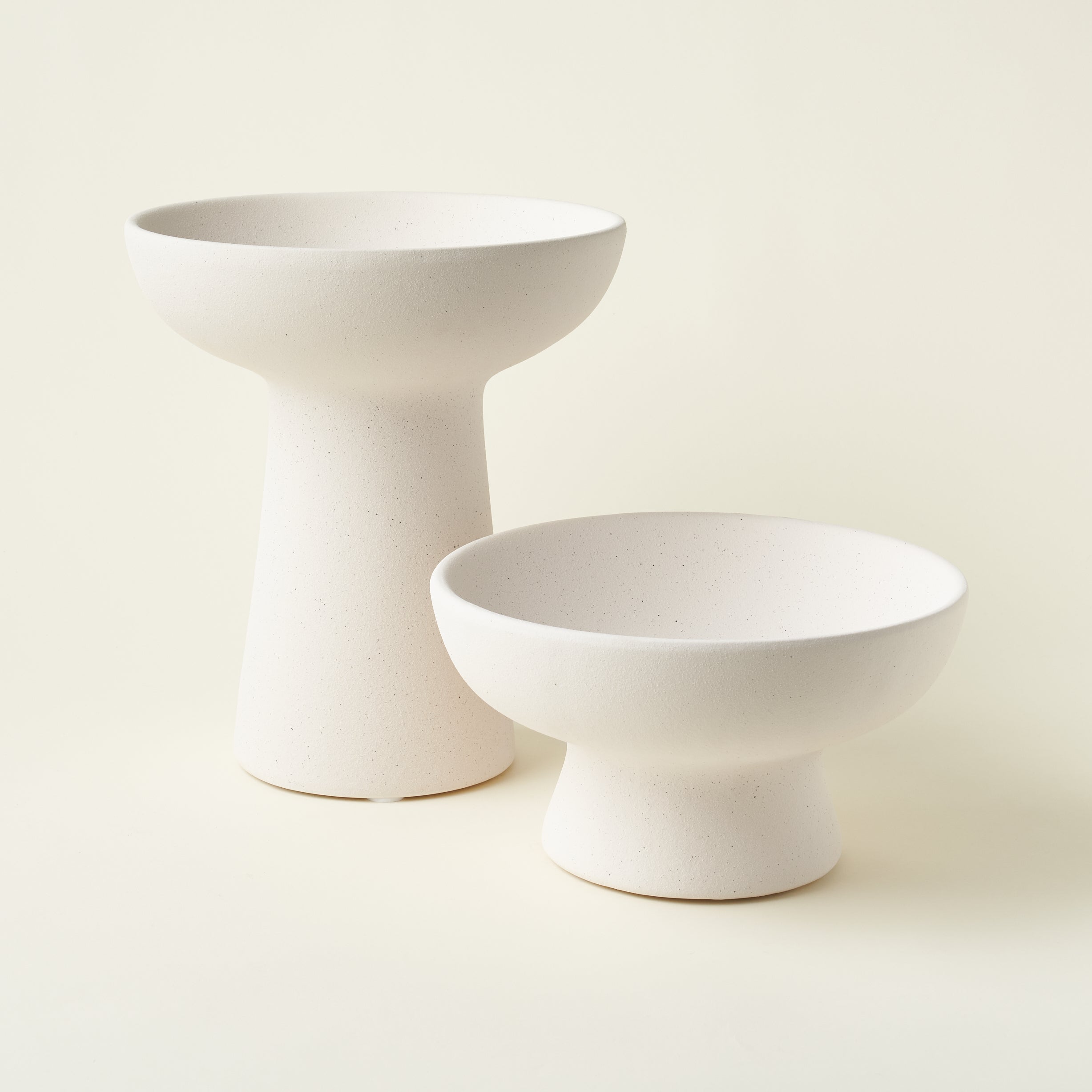 A set of two ceramic compotes in two different sizes, styled together to show their varied heights.