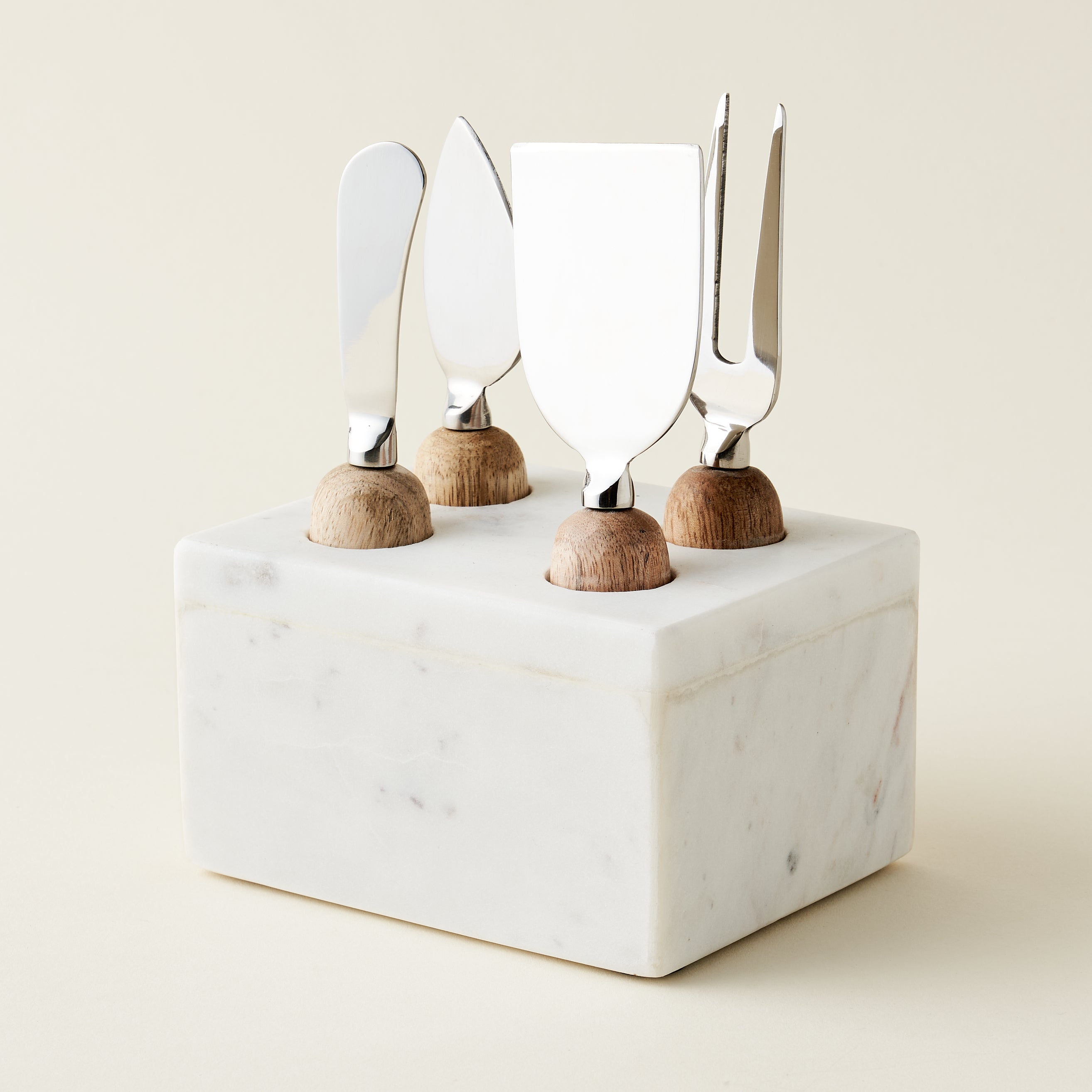 A set of cheese knives in a marble stand.