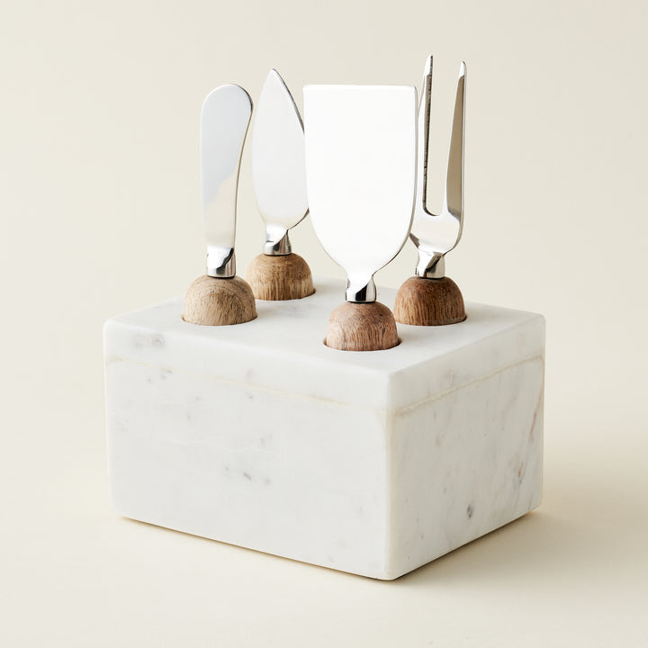 A set of cheese knives in a marble stand.