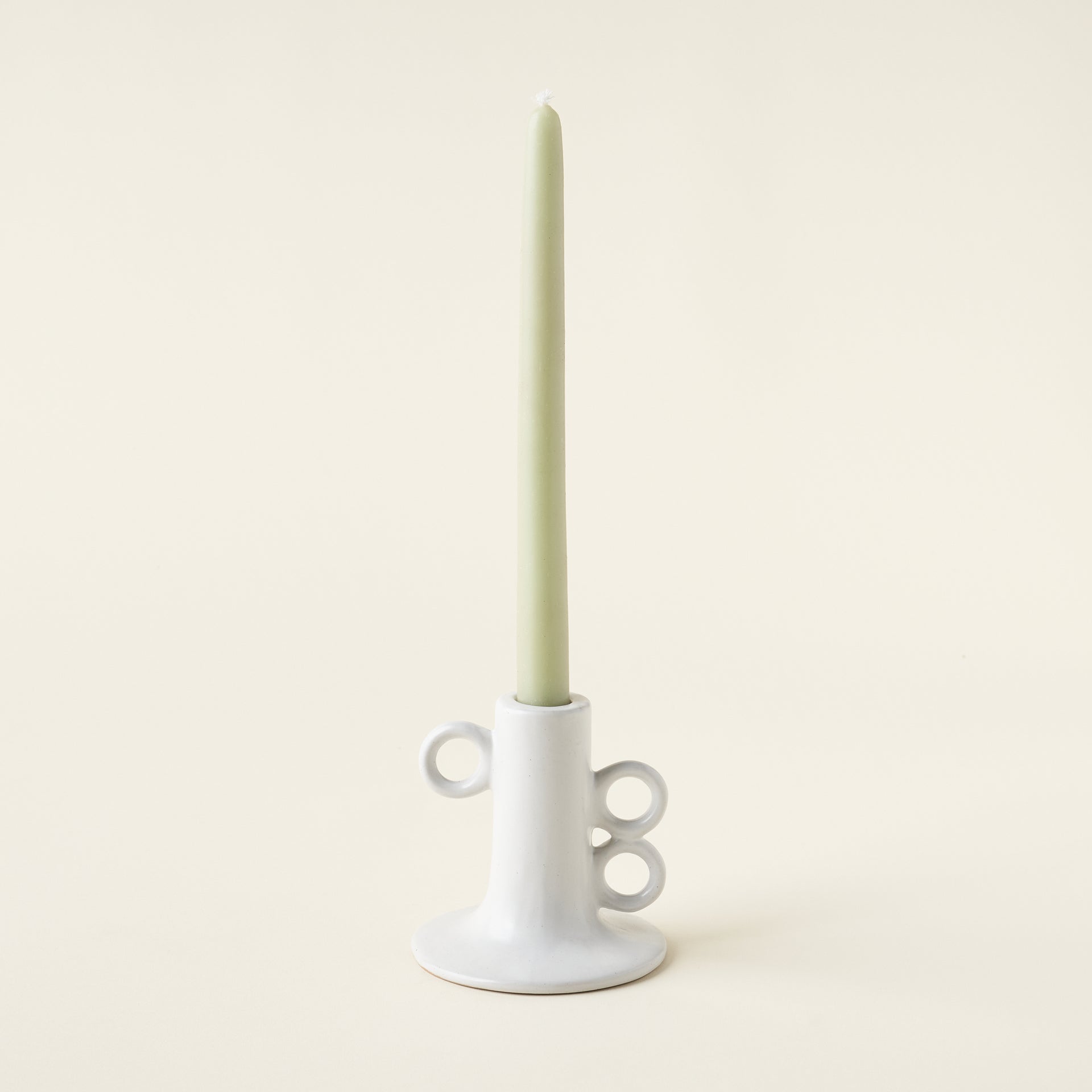 Stoneware taper holder with a matte white finish and circular handles.