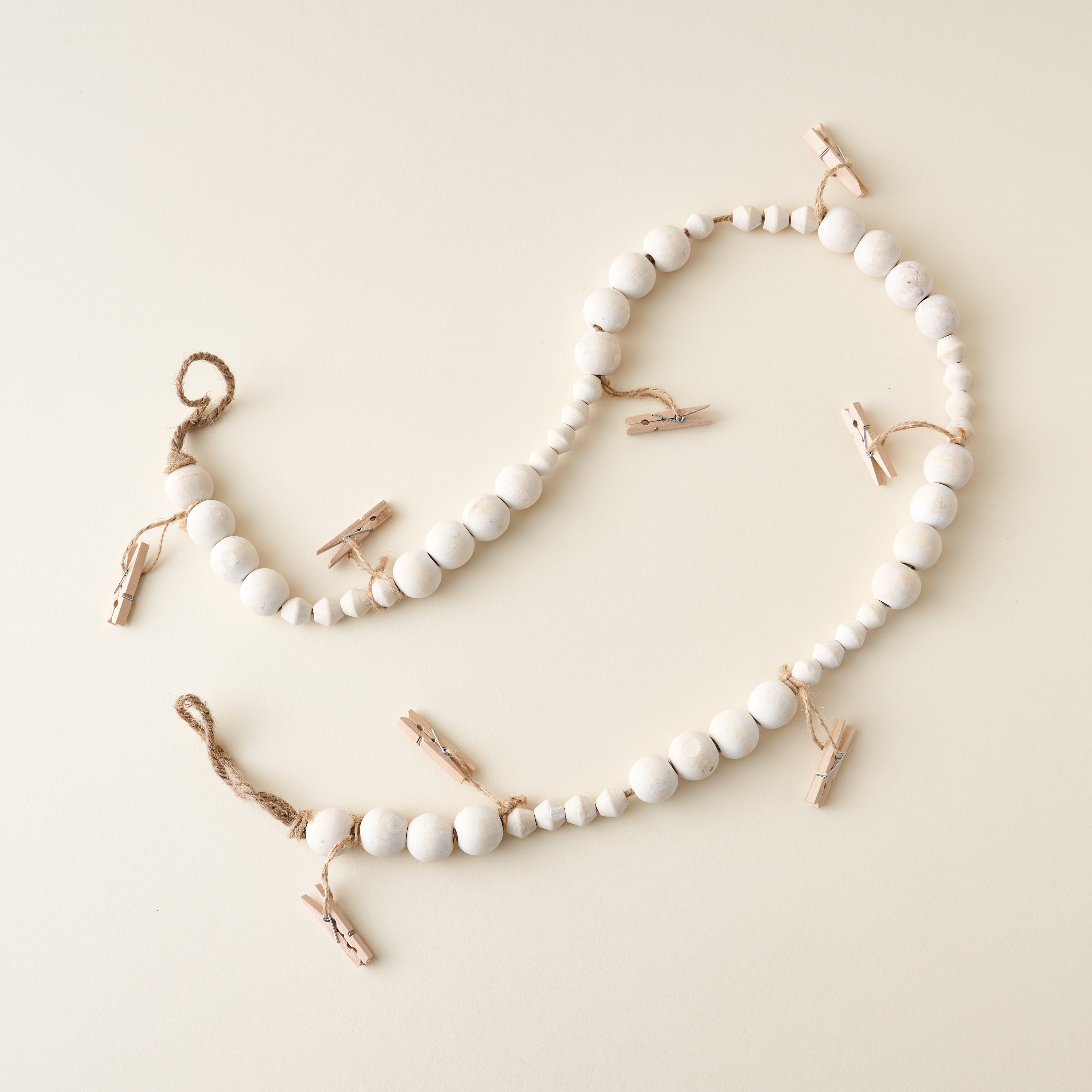 A wooden garland with small clothes pins clipped to it.