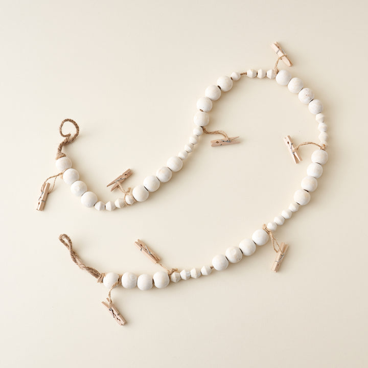 A wooden garland with small clothes pins clipped to it.