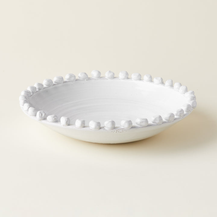 A decorative, off-white ceramic bowl with a unique raised dotted texture.