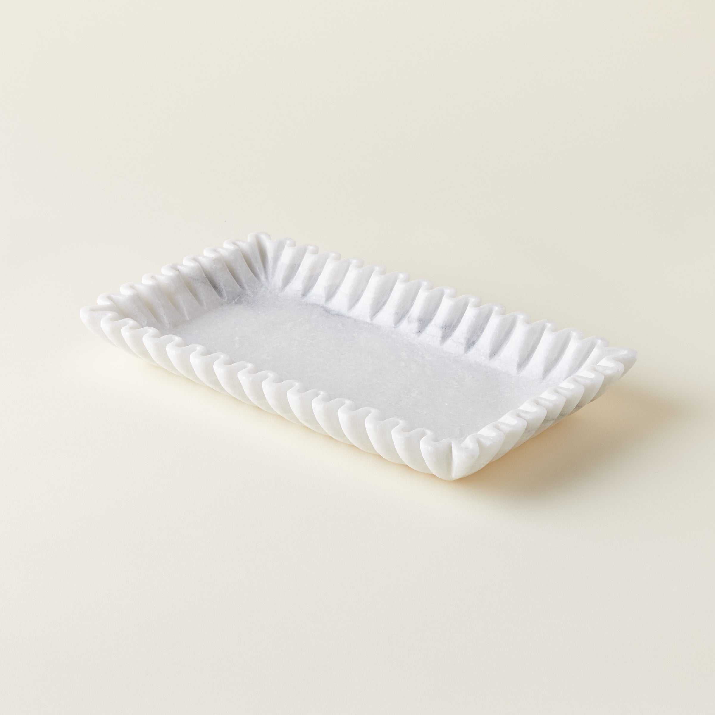 Close-up of the elegant fluted texture and natural tonal variations of the white marble platter.