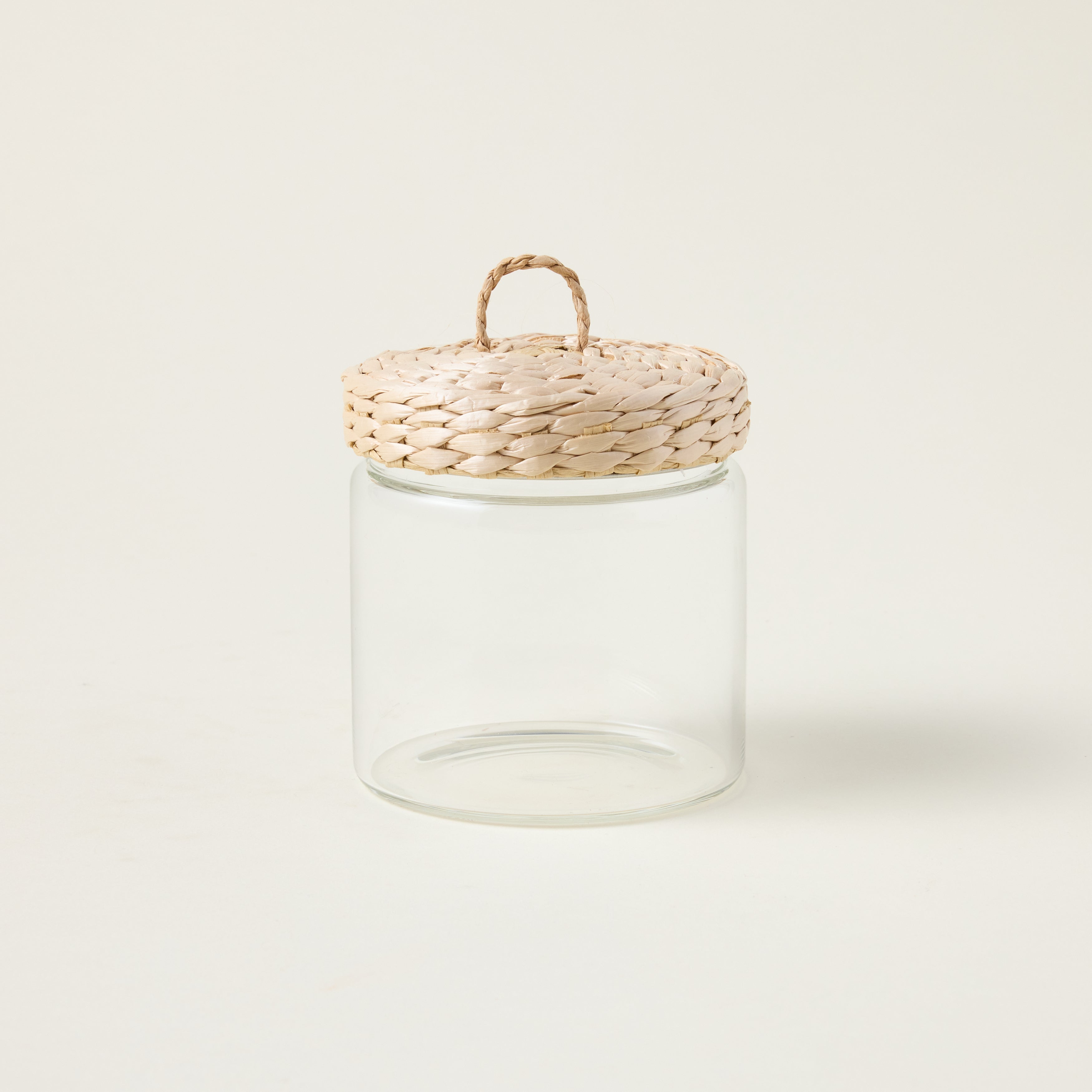 Glass storage jar with a handwoven lid made from natural grass, showcasing an organic and refined aesthetic.