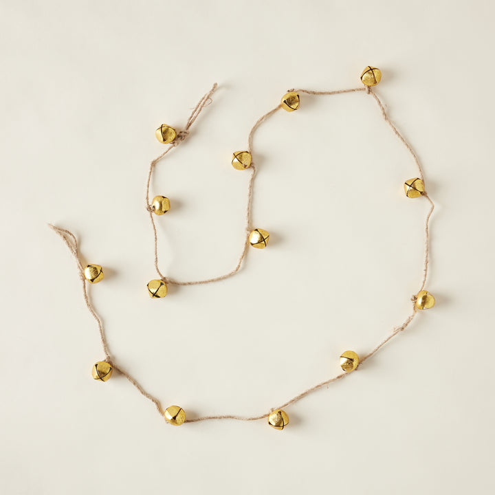 A garland with small, rustic metal bells strung along a natural jute rope.