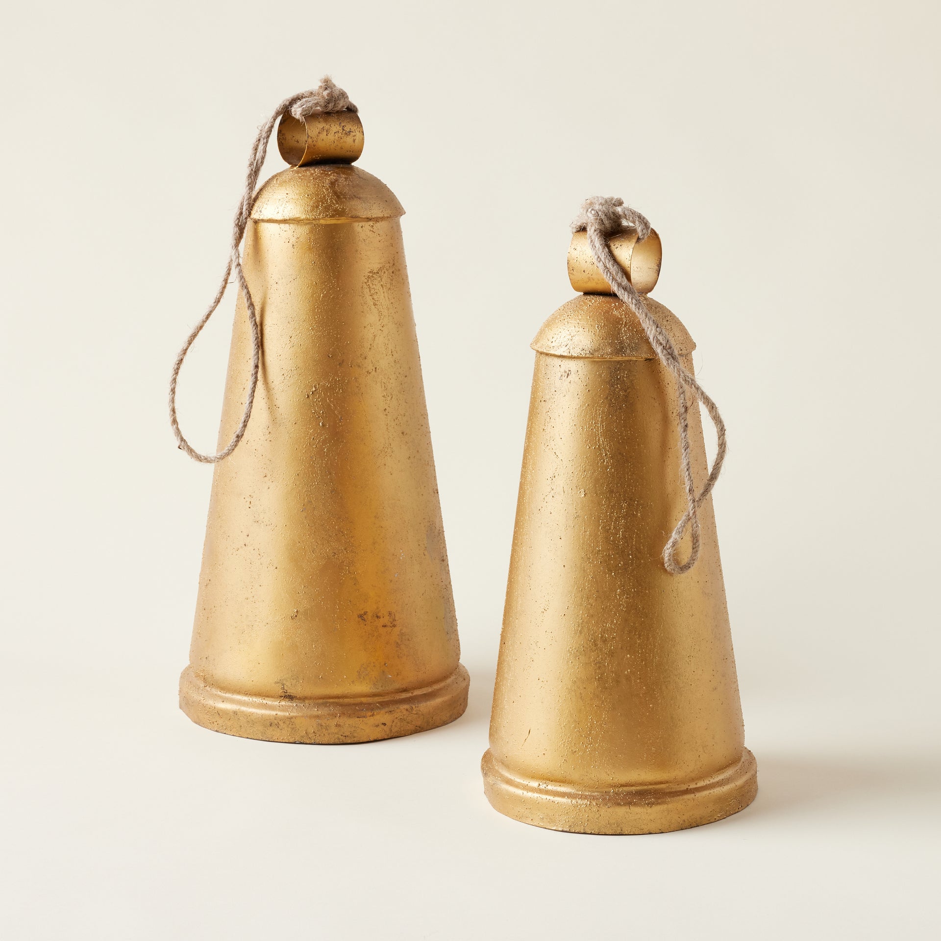 A beautiful way to add vintage charm to your holiday decor. Made of metal with a rich antique gold finish, this set of two Antique Gold Hanging Bells brings a beautiful, collected feel to your home. Complete with a natural jute rope hanger, these bells are the perfect way to add a warm, festive touch to any space.