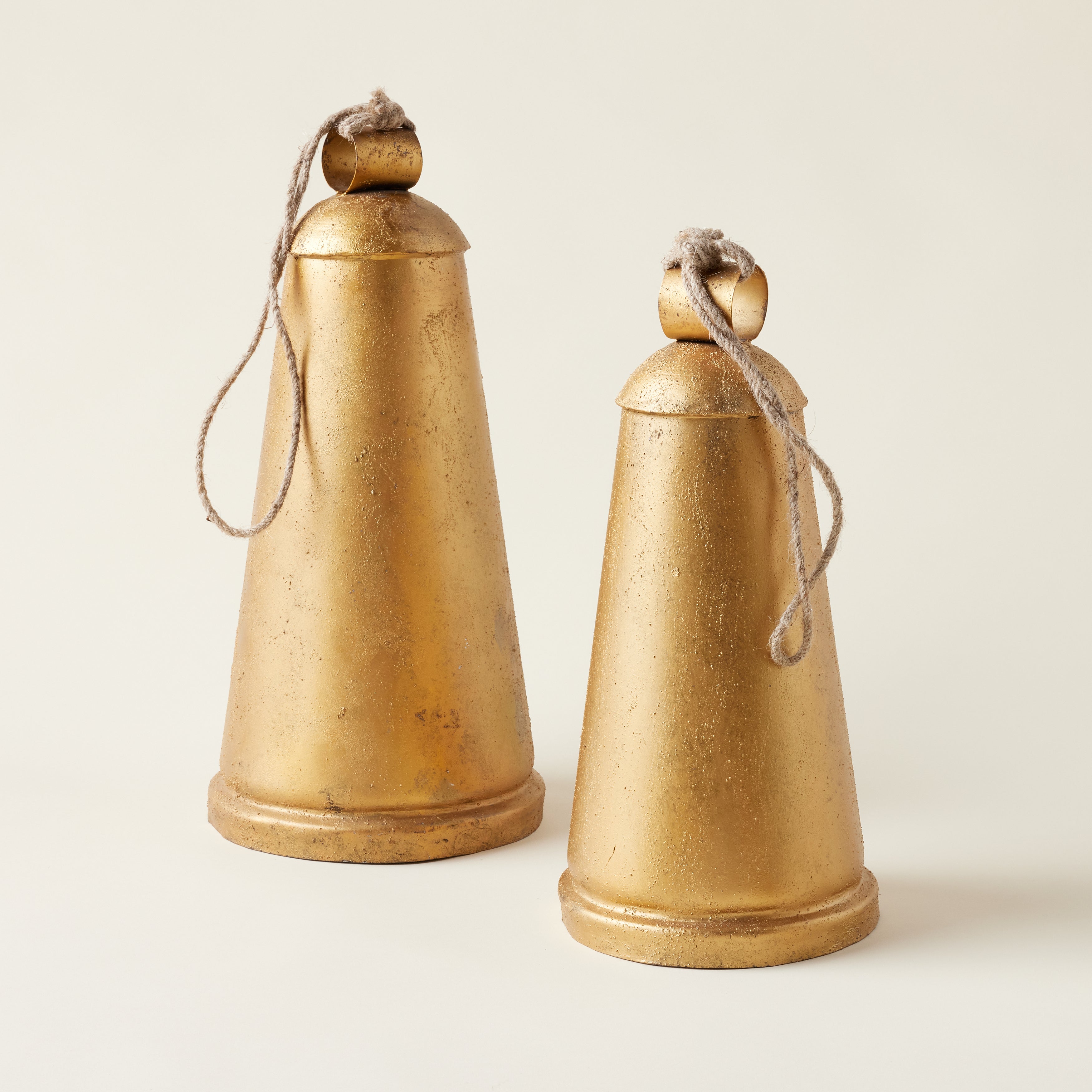 A beautiful way to add vintage charm to your holiday decor. Made of metal with a rich antique gold finish, this set of two Antique Gold Hanging Bells brings a beautiful, collected feel to your home. Complete with a natural jute rope hanger, these bells are the perfect way to add a warm, festive touch to any space.