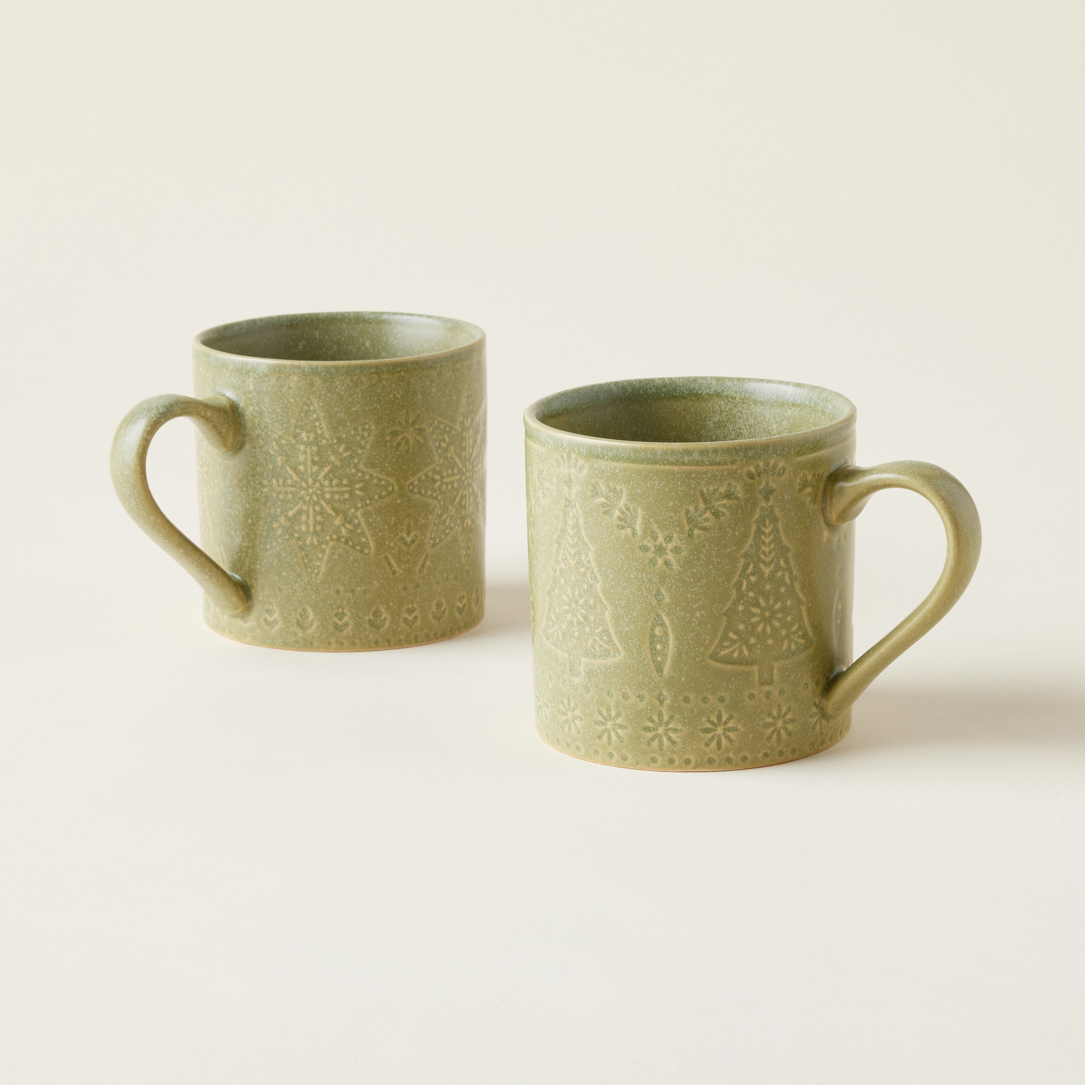 A stoneware mug with a matte green glaze and a debossed snowflake design.