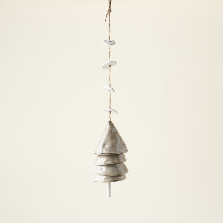 A set of hanging stoneware bells in beige and white with a jute string.