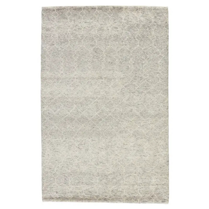 A hand-knotted Indira rug with a gray backdrop, a white diamond trellis design, and a scalloped edge.