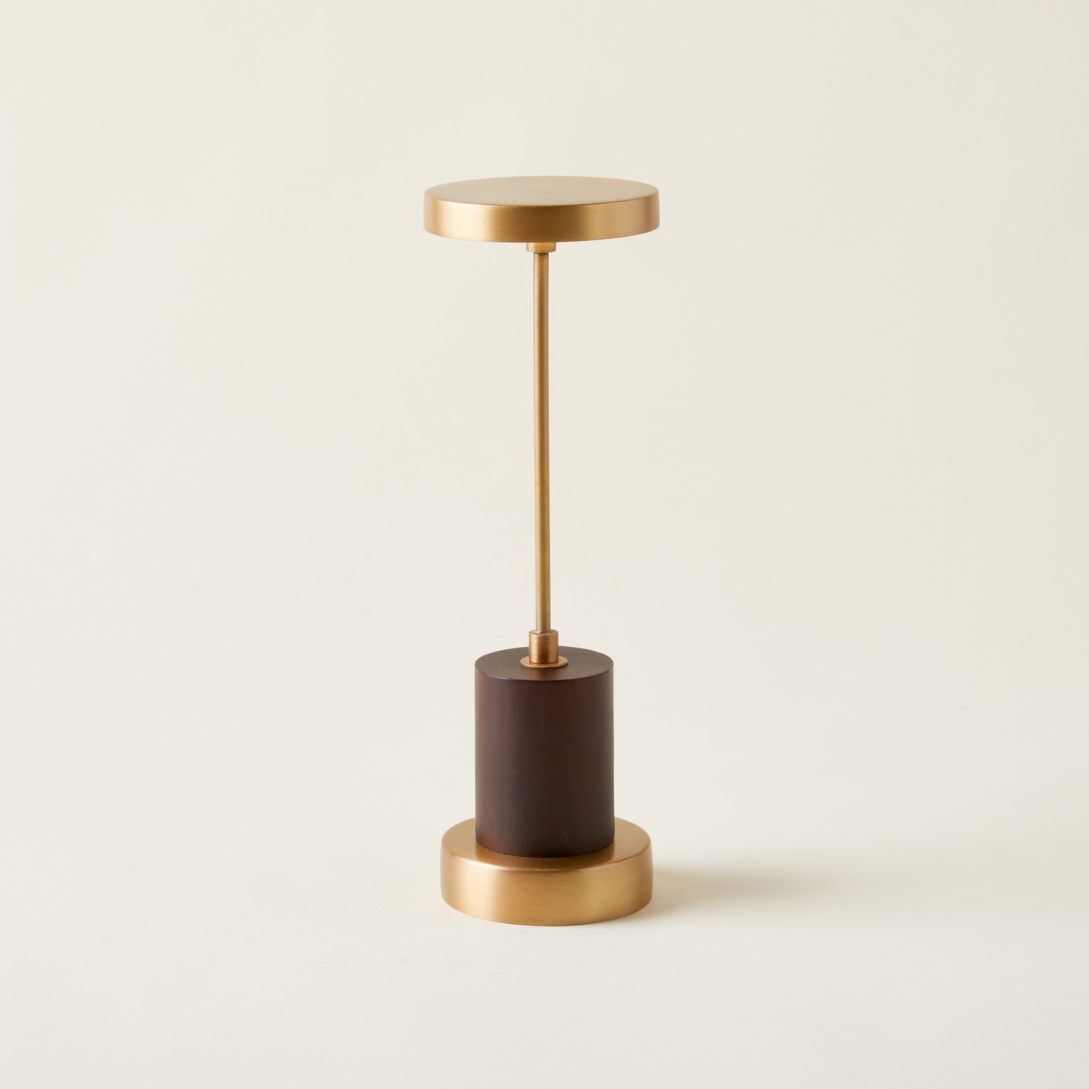 Table lamp with an antique brass finish and a genuine mango wood base, featuring a sculptural and refined design.