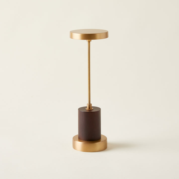 Table lamp with an antique brass finish and a genuine mango wood base, featuring a sculptural and refined design.