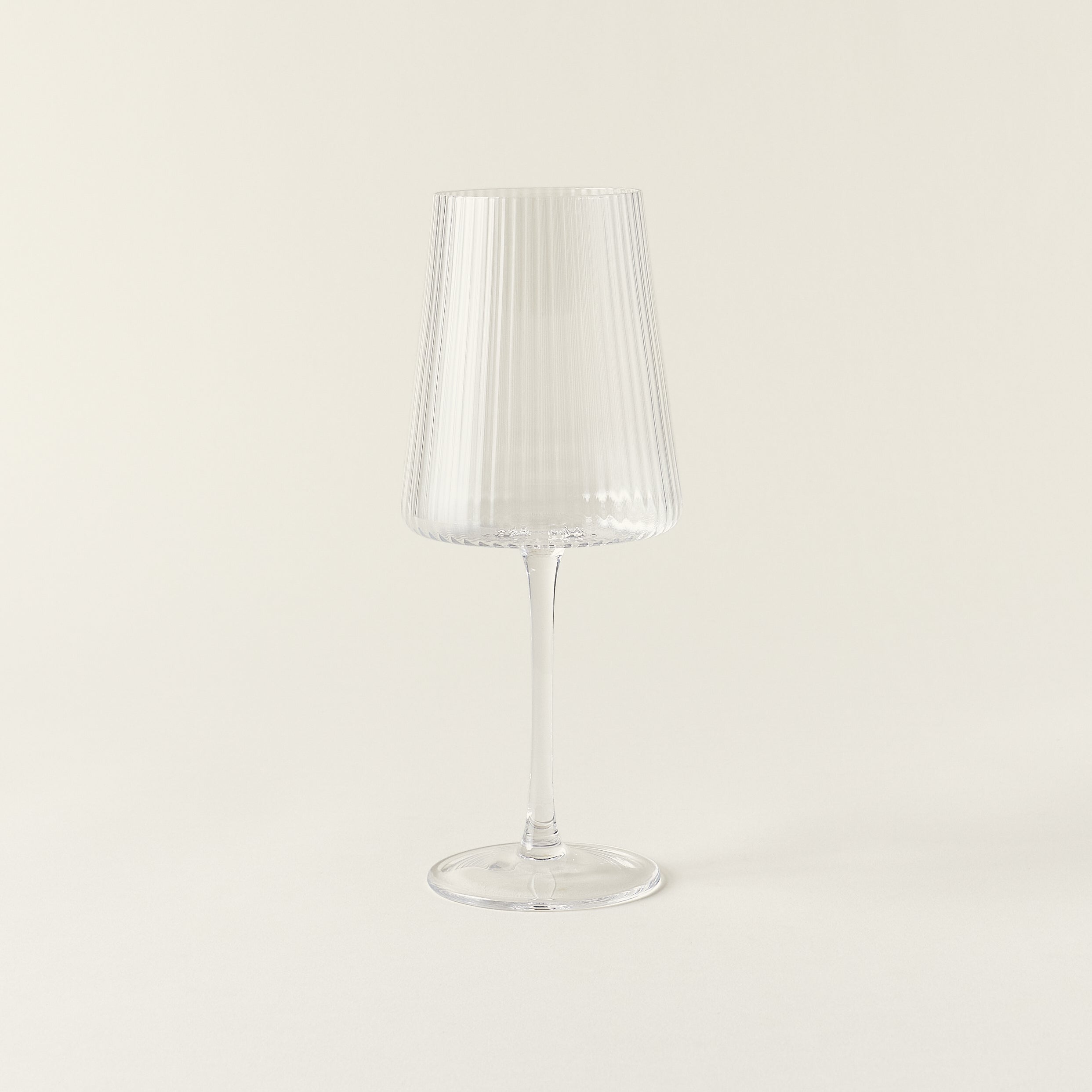 A clear wine glass with a delicate, fluted texture and a smooth rim.