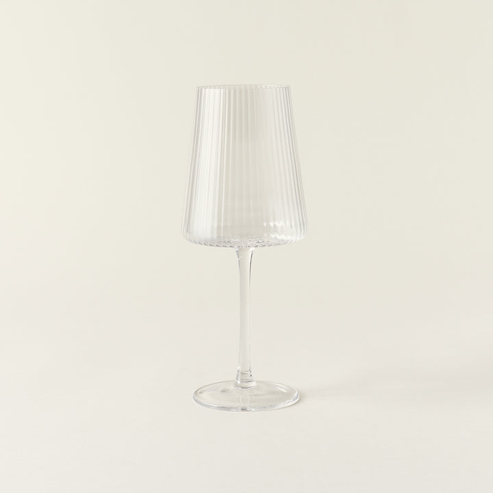 A clear wine glass with a delicate, fluted texture and a smooth rim.