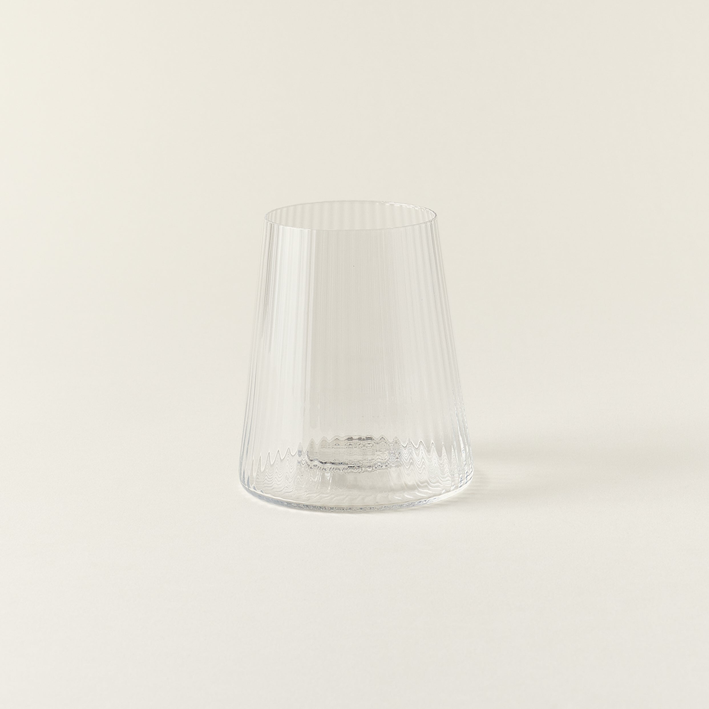 A clear drinking glass with a delicate, fluted texture and a smooth rim.
