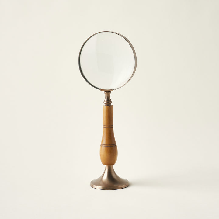 Antique magnifying glass on a stand with a brass and bone body and a timeless, heirloom design.