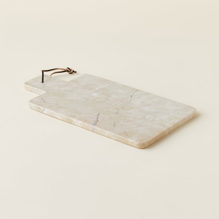 A rectangular sage-colored marble cheese board with a handle and leather loop.
