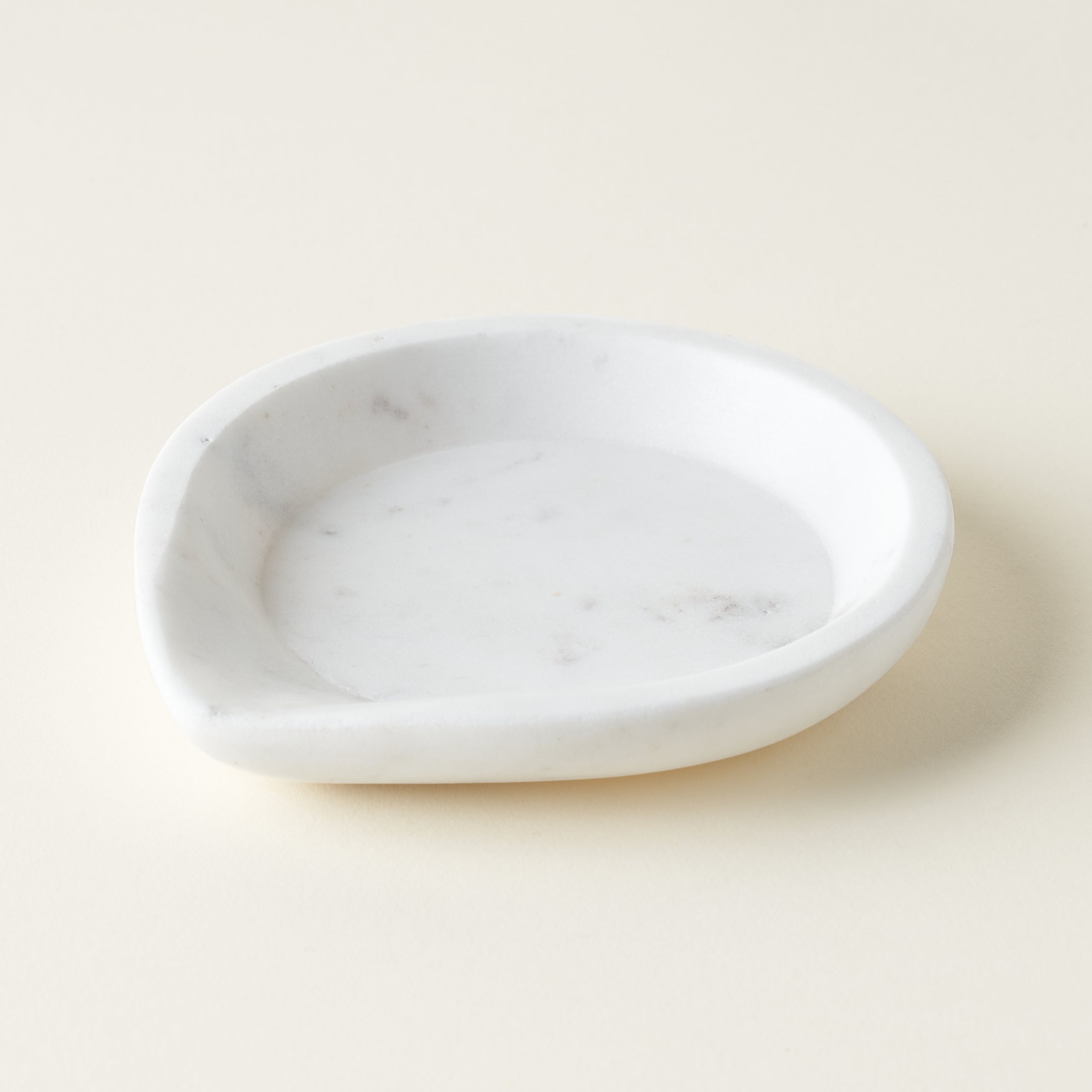 A smooth, white marble spoon rest with a carved indentation for holding utensils.