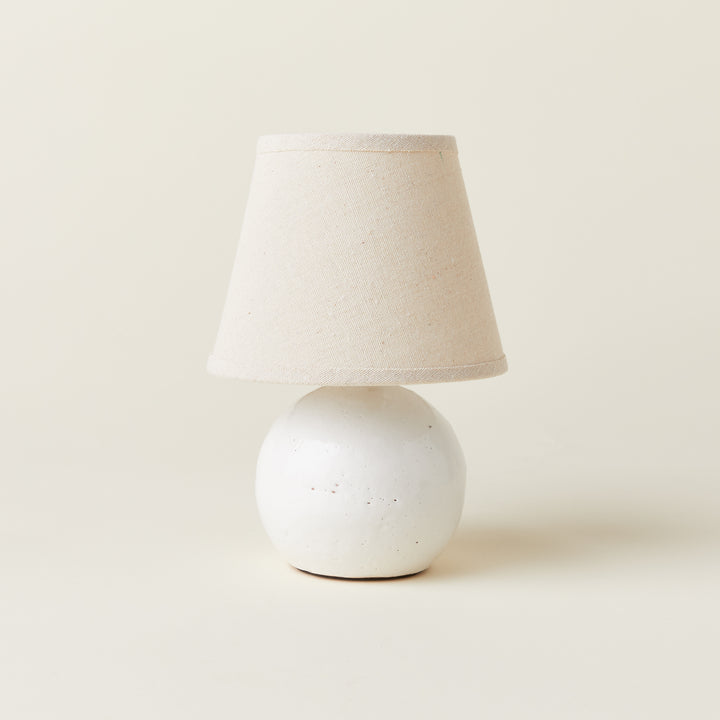 A petite off-white ceramic lamp with a textured cream-colored shade.
