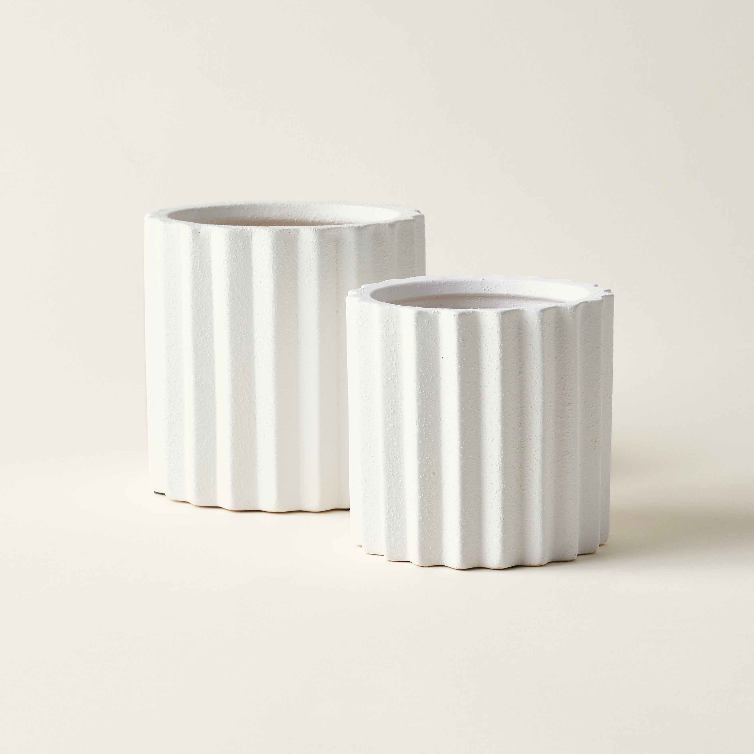 Set of two white ceramic planters with a fluted texture.