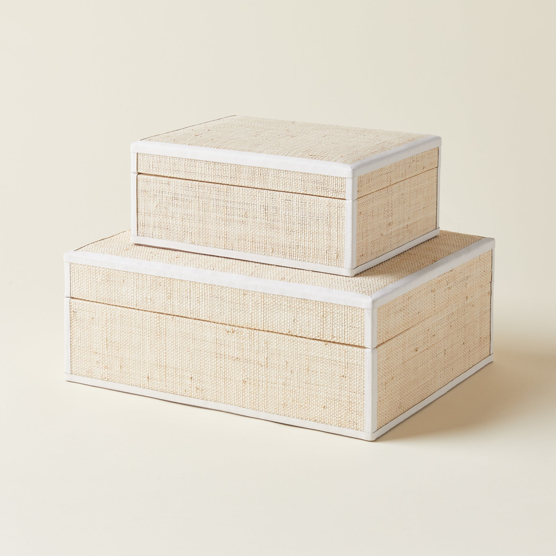 A decorative storage box with a hinged lid, made from natural woven raffia and finished with leather trim.