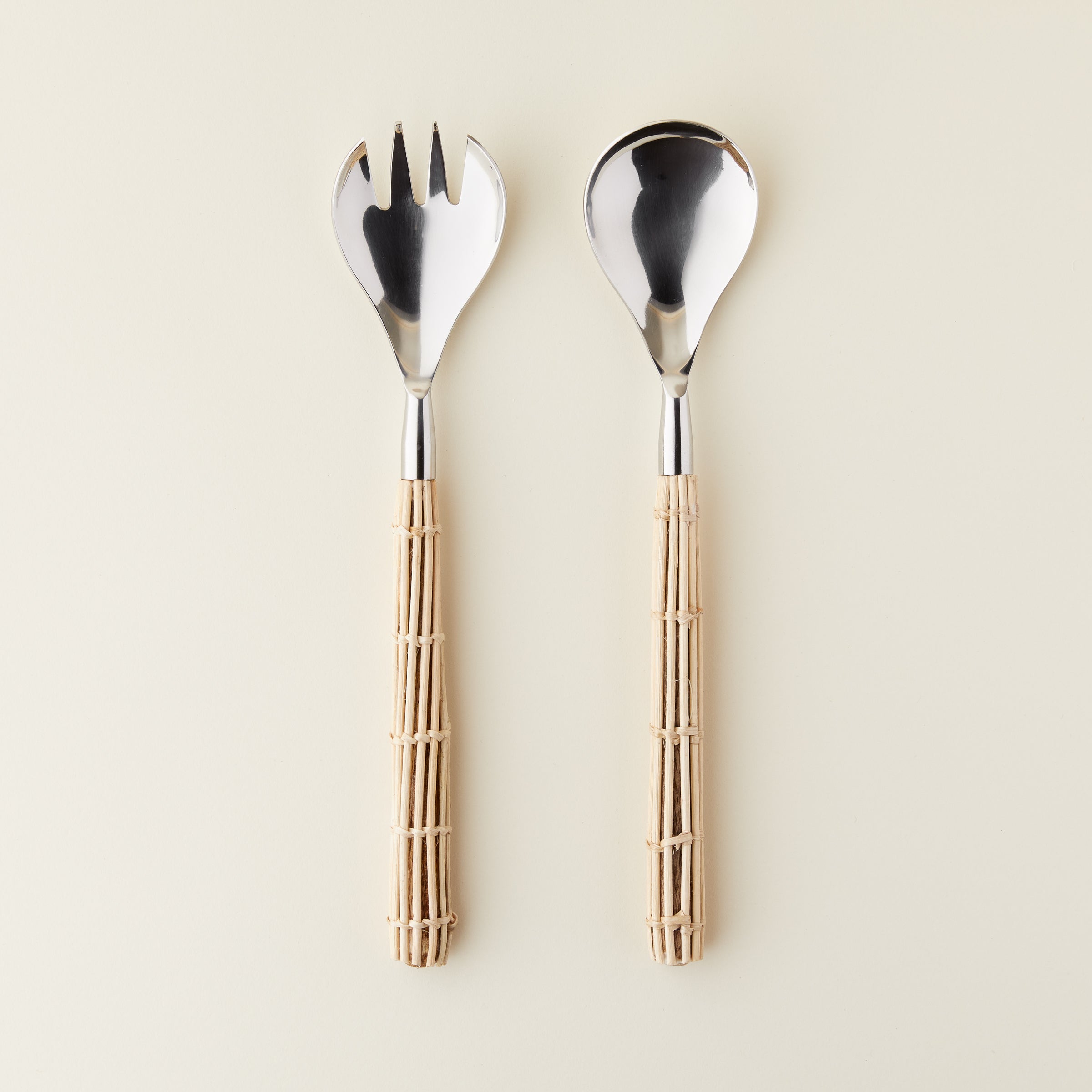 Luxury rattan salad servers with stainless steel ends and woven rattan handles.
