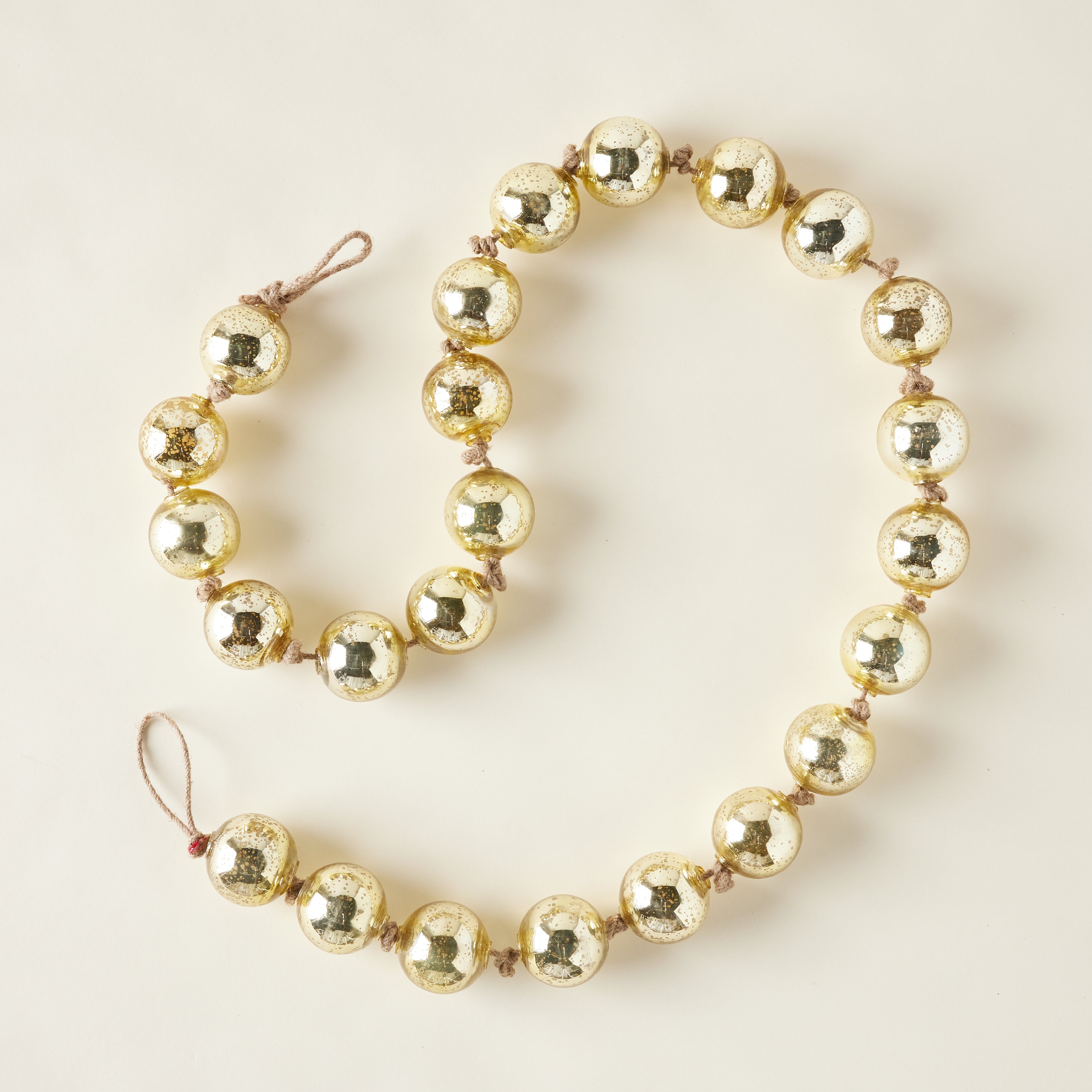 A decorative garland made of small, gold-colored glass ornaments and a jute string.