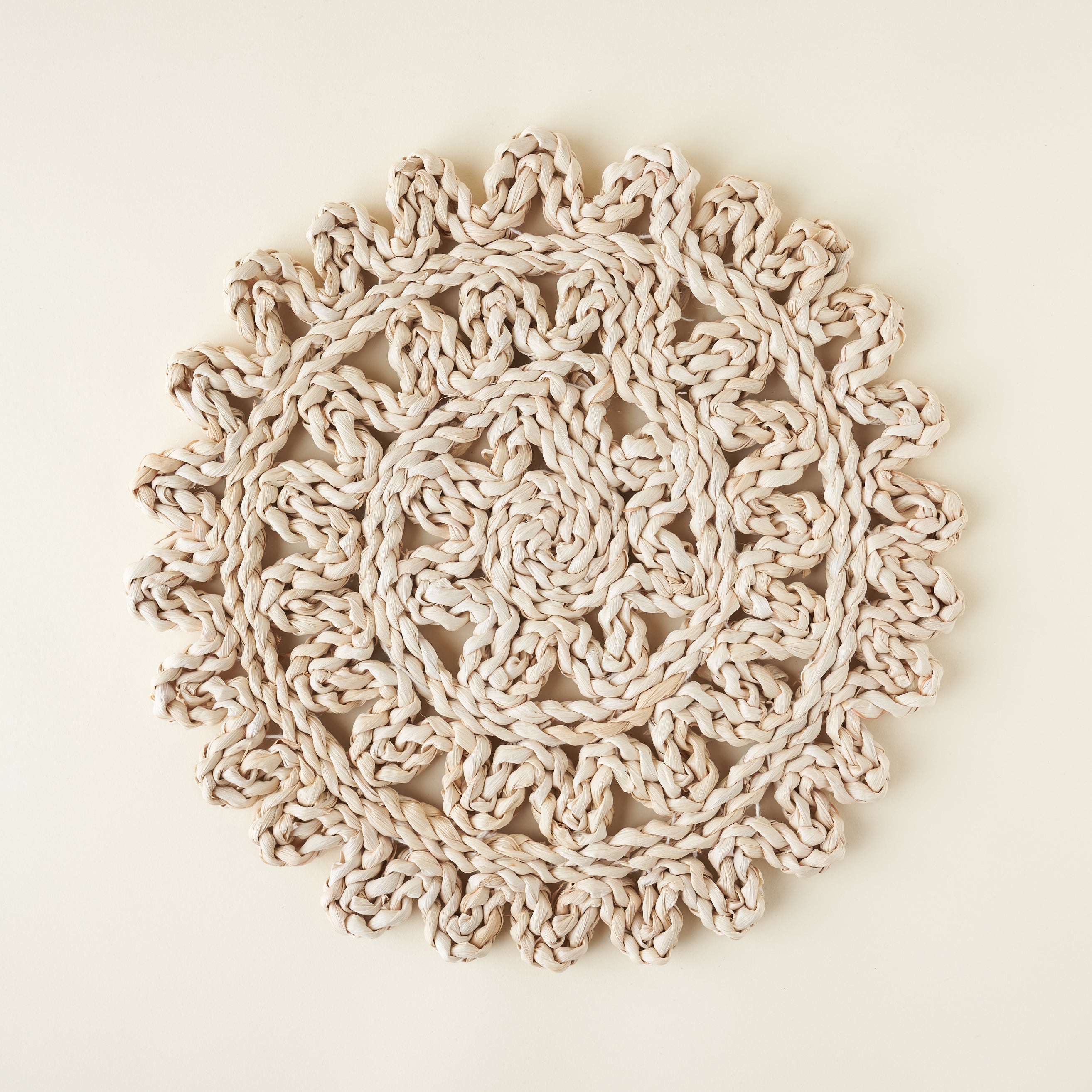 Round woven straw placemat, showing a detailed texture and neutral tones.
