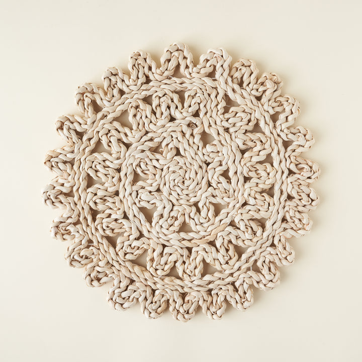 Round woven straw placemat, showing a detailed texture and neutral tones.
