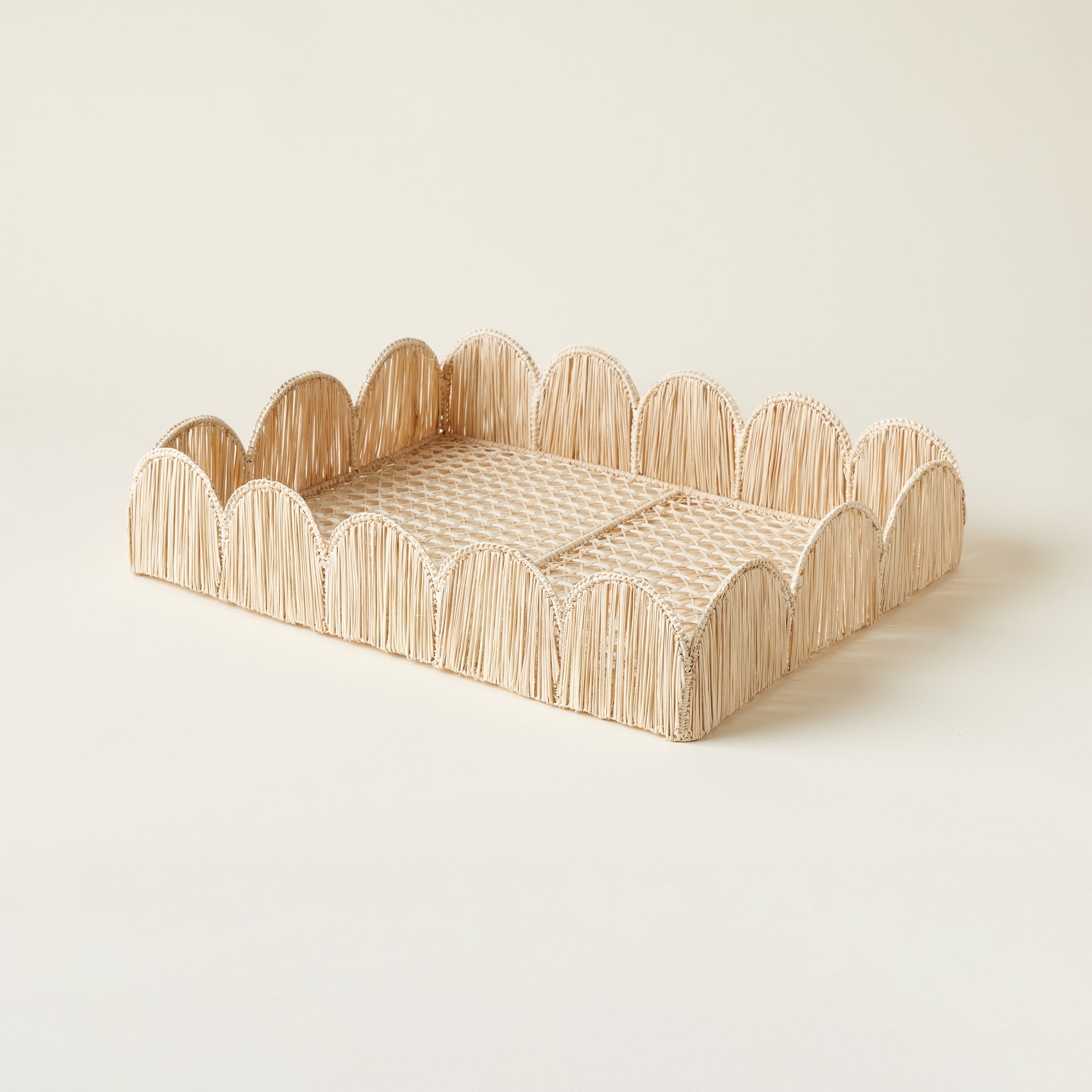 A handwoven rectangular tray with a scalloped edge, made from natural iraca fiber.