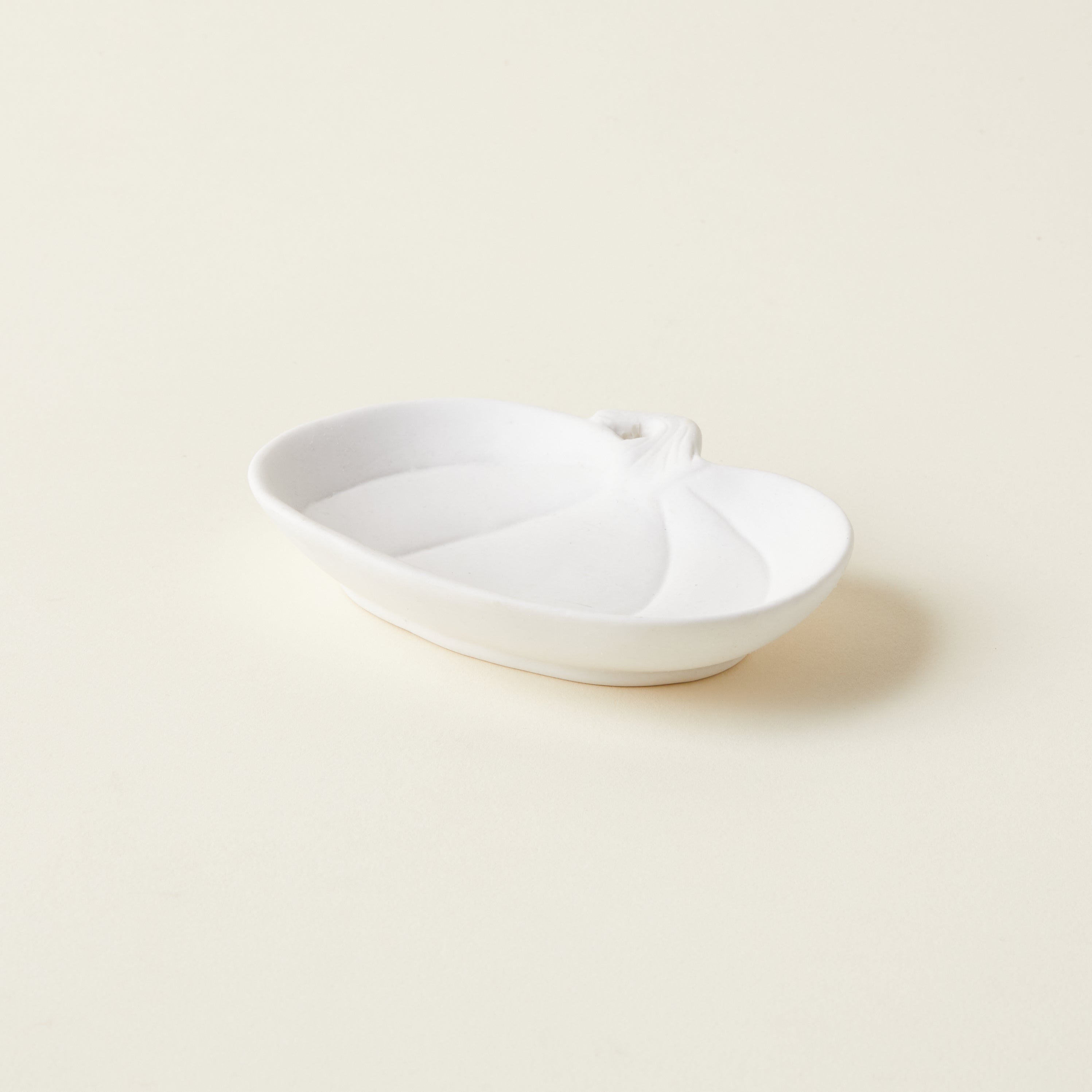 Petite white stoneware pumpkin-shaped dish, styled on a book stack for a whimsical autumn accent.