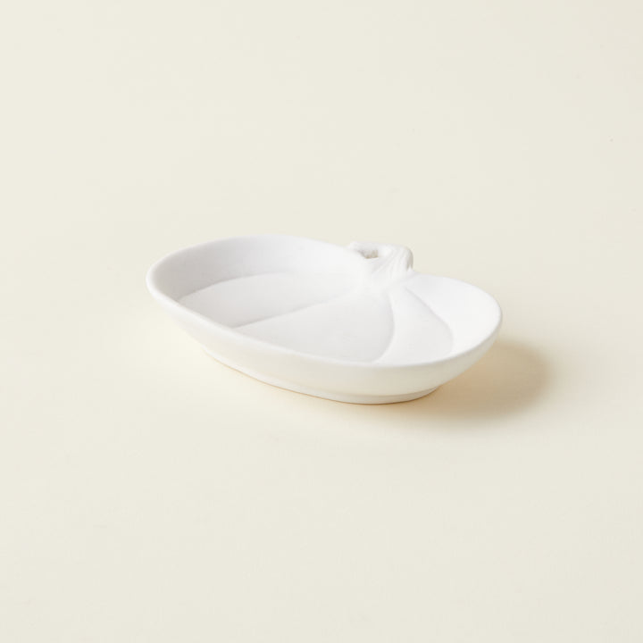 Petite white stoneware pumpkin-shaped dish, styled on a book stack for a whimsical autumn accent.