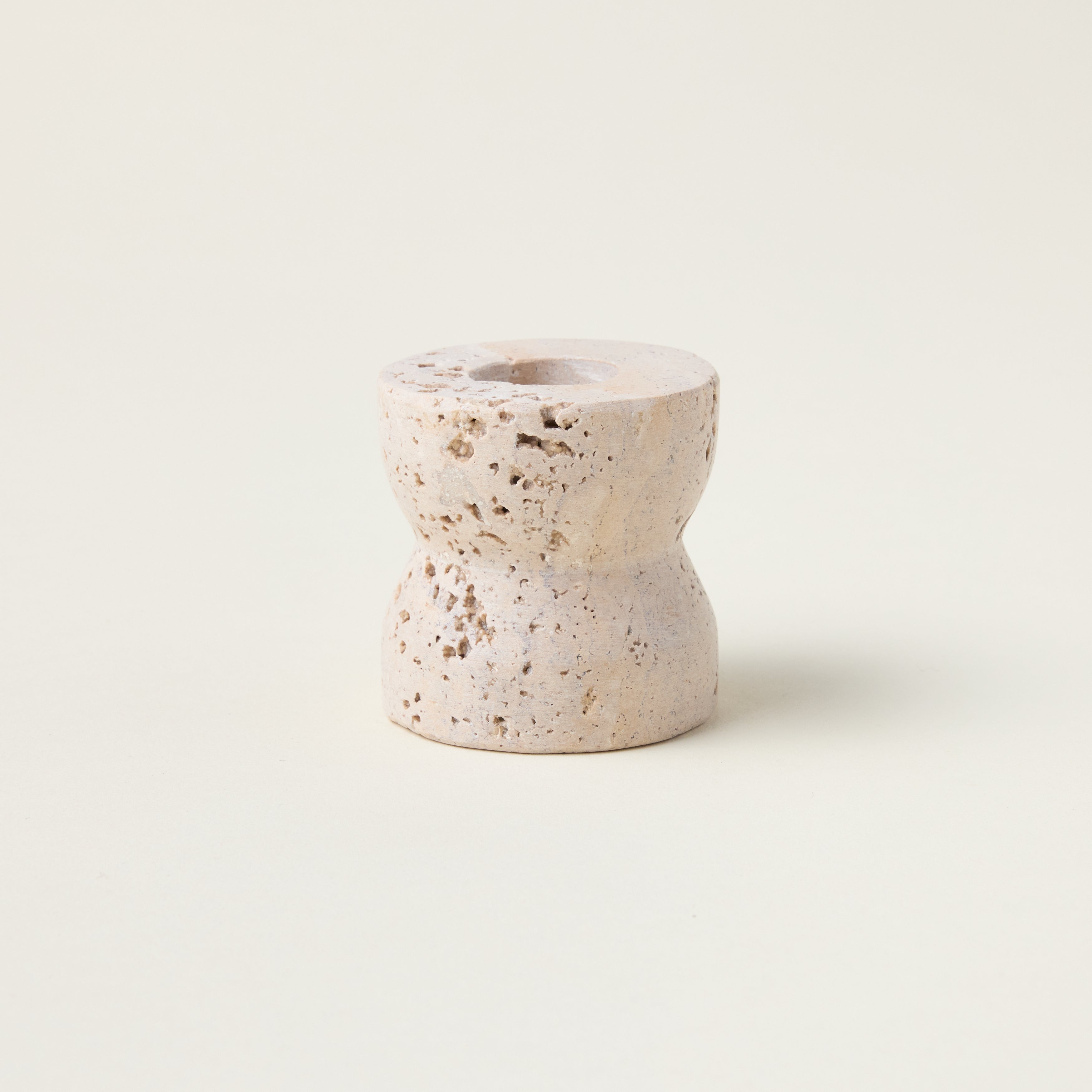 Sculptural taper candle holder crafted from genuine travertine marble with a smooth, refined finish.