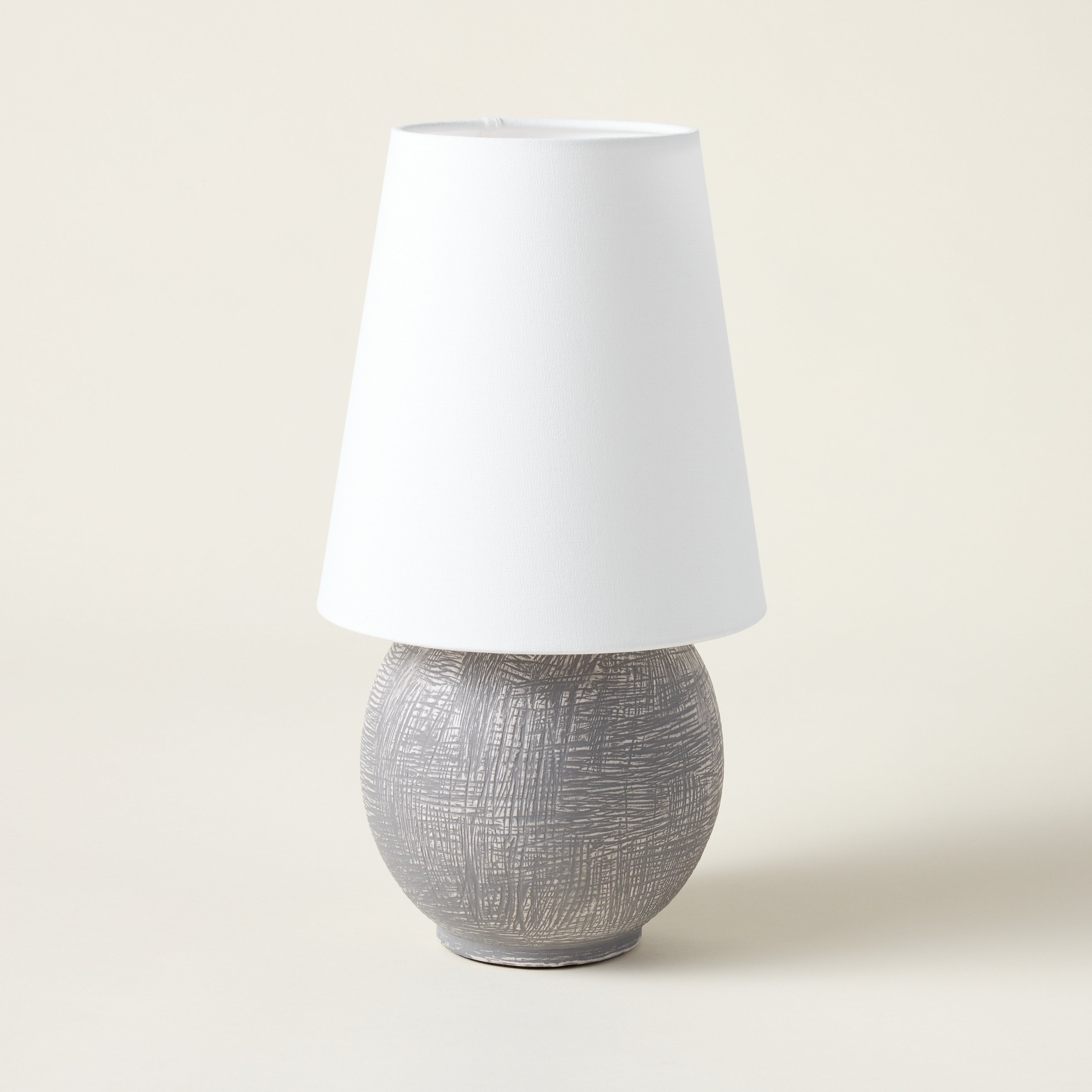 Sculptural rechargeable table lamp with a spherical ceramic base and an oversized linen shade.