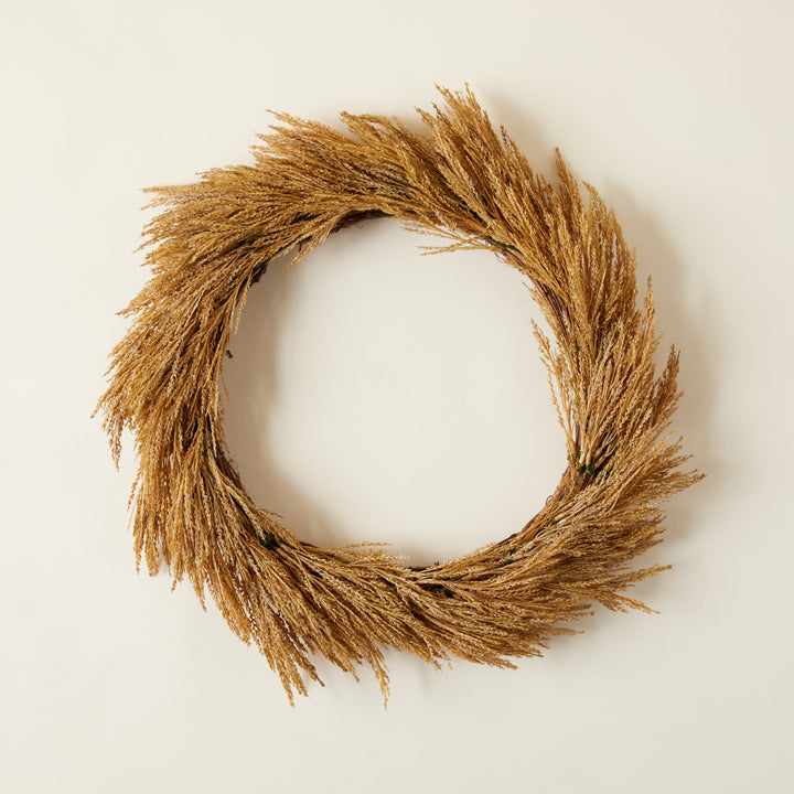 Handcrafted wheat wreath in a dark gold hue with a natural, organic texture.