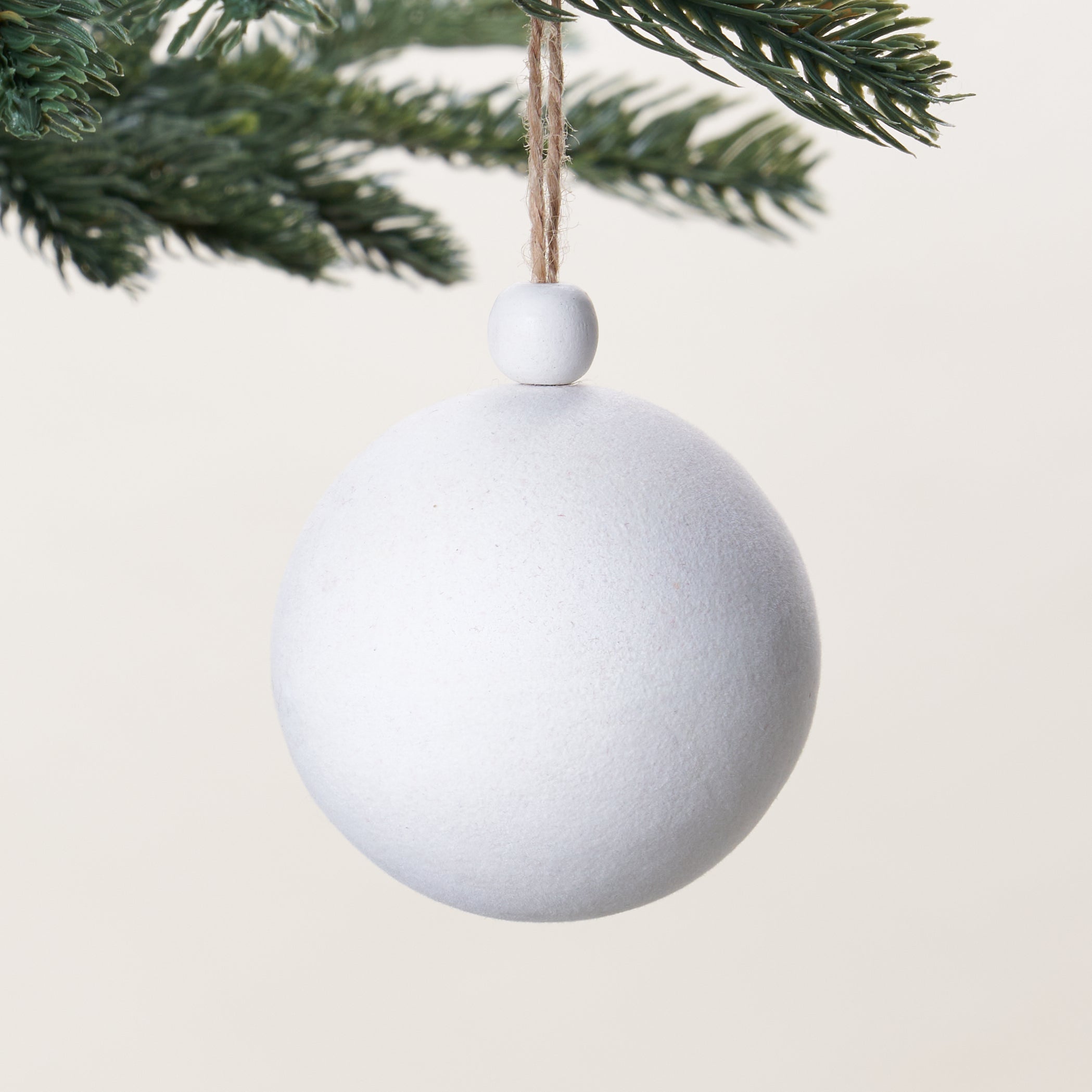 A decorative ornament with a white flocked finish and a wooden bead on top.