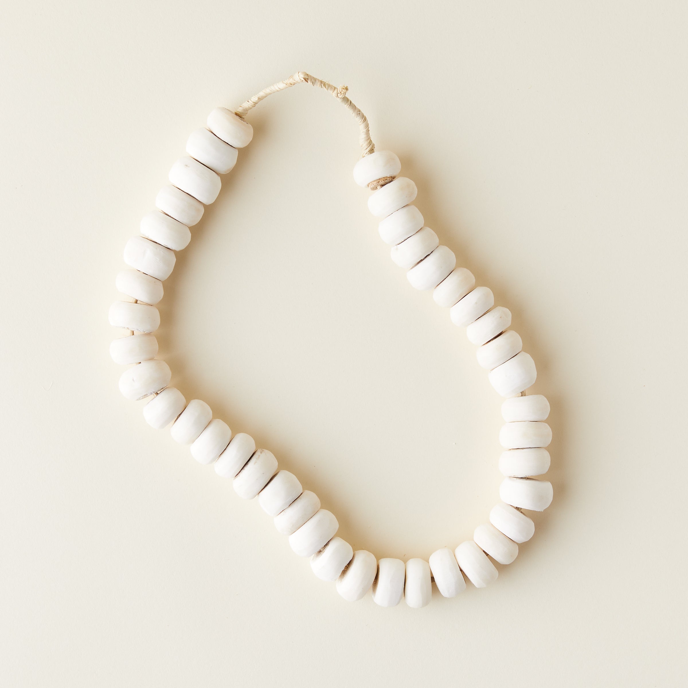 A collection of small, off-white bone beads with a natural, varied finish.