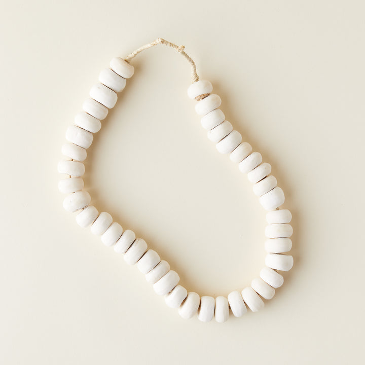 A collection of small, off-white bone beads with a natural, varied finish.