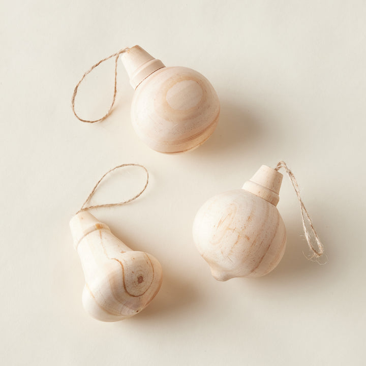 A boxed set of three decorative carved wood ornaments, each in a different shape with an intricate carved design.