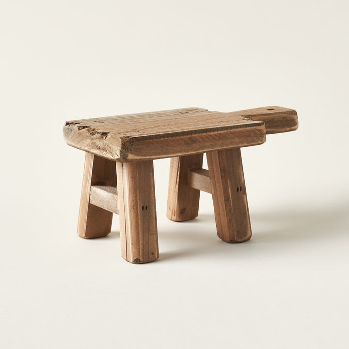Handcrafted wooden riser with a natural wood grain, used as a display stand for a candle.