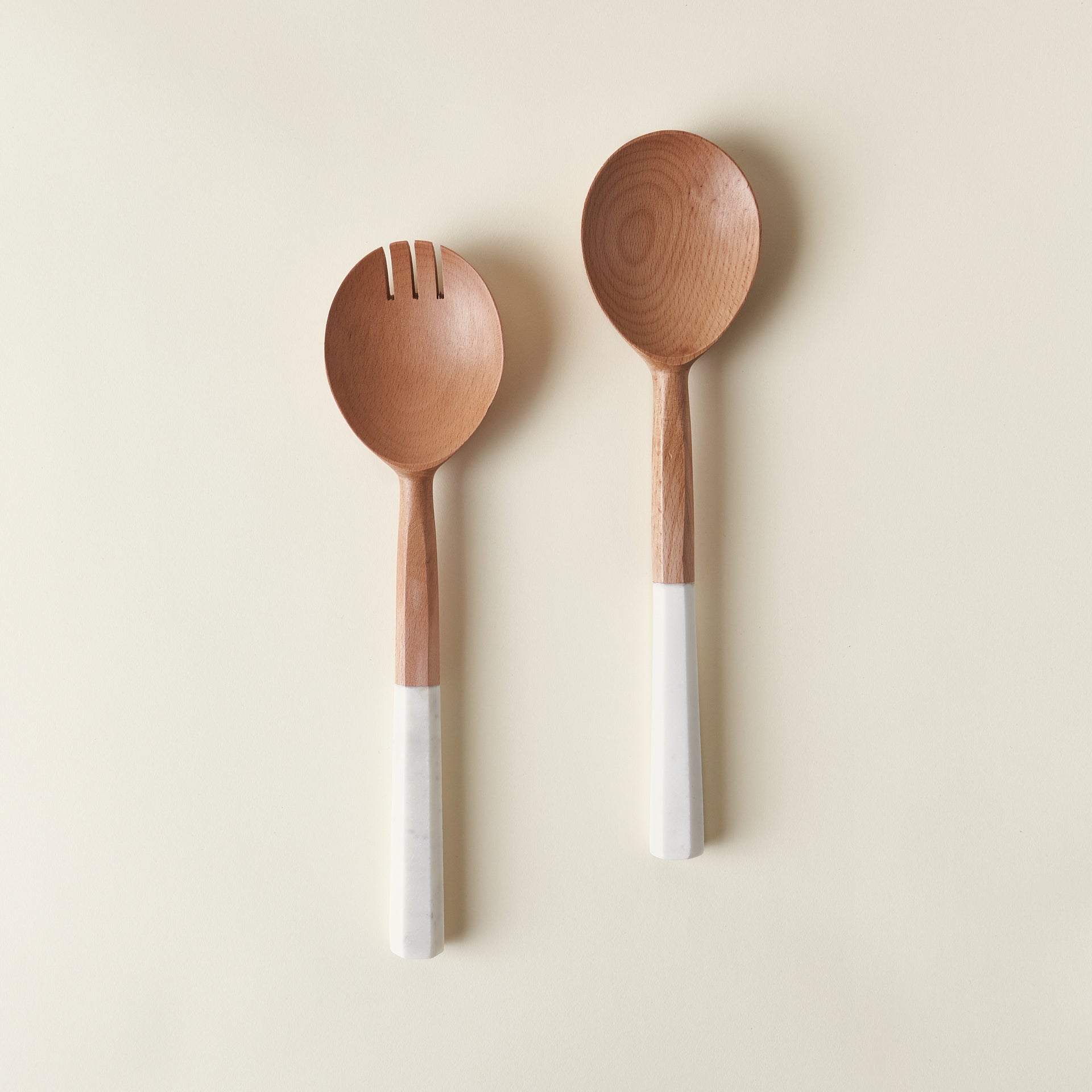 Crete salad servers with wood handles and hexagon-shaped white marble heads.