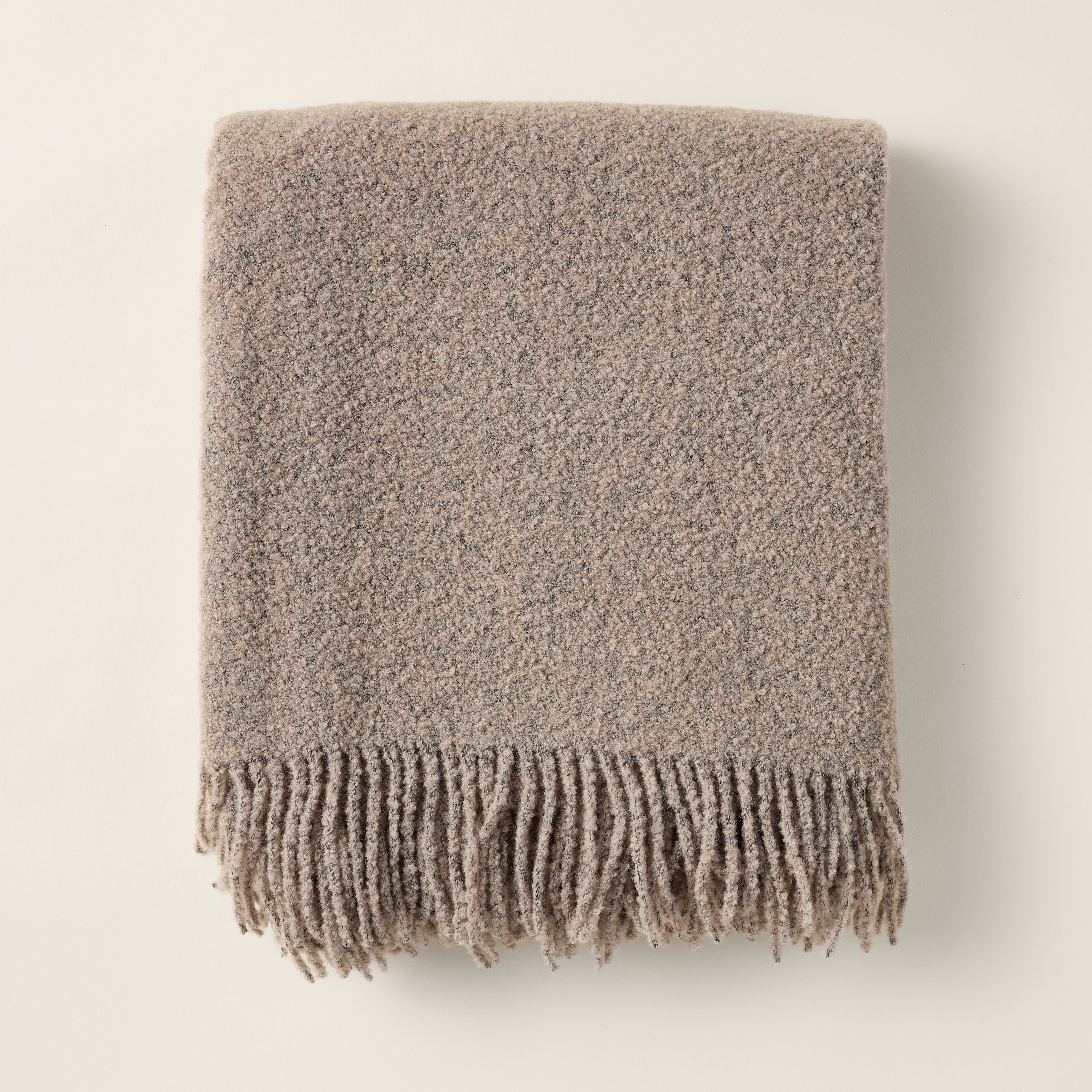 Wool boucle throw with a rich, textural weave, styled for a cozy and layered look.