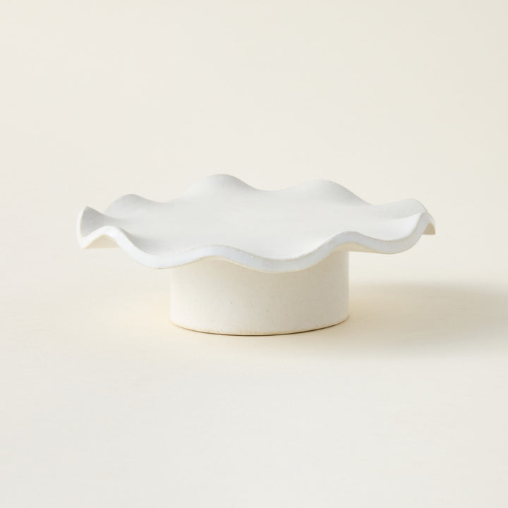 A hand-crafted white glazed stoneware pedestal with a delicate ruffle edge.